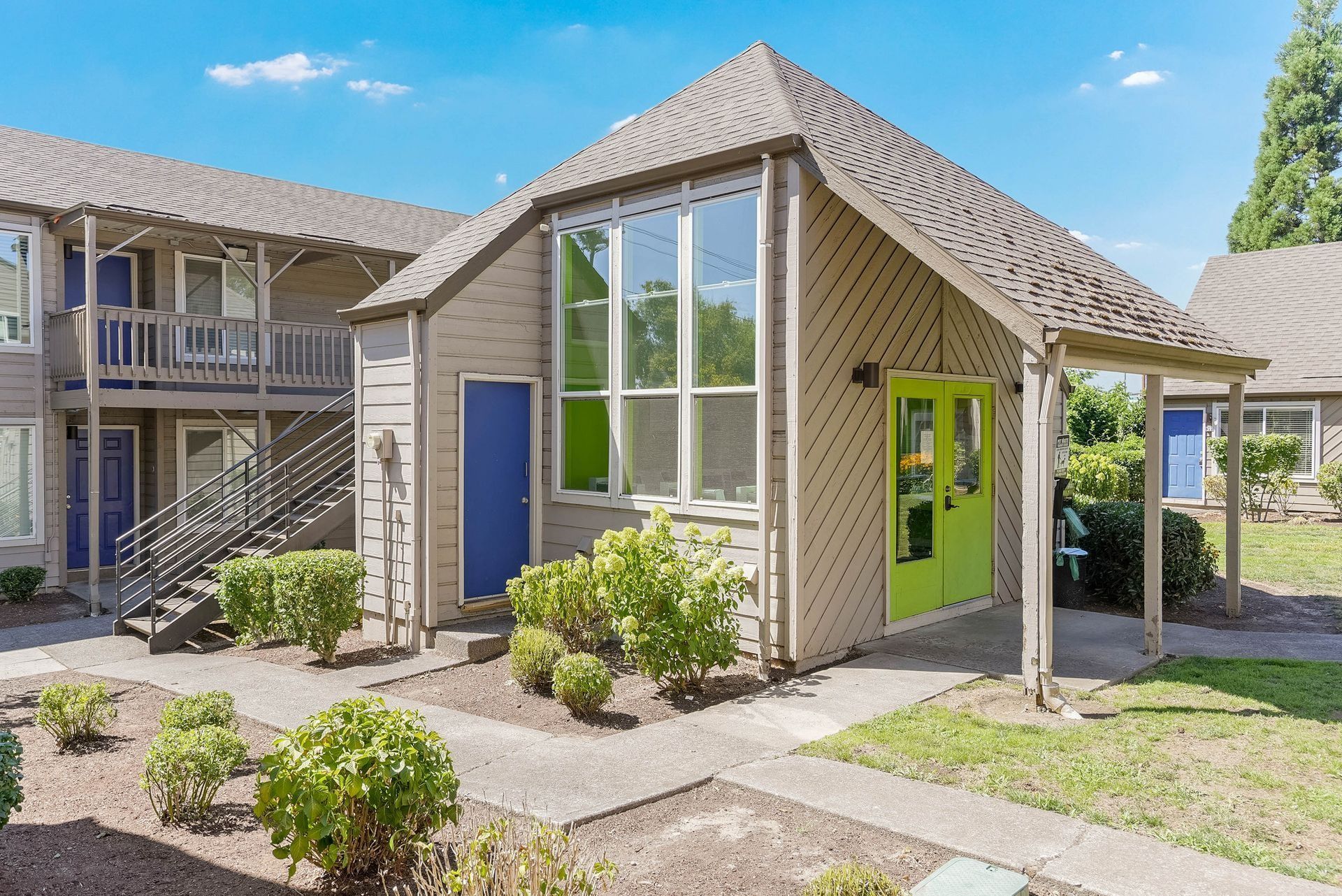Small modern house with blue and lime green doors, front steps, and a courtyard path