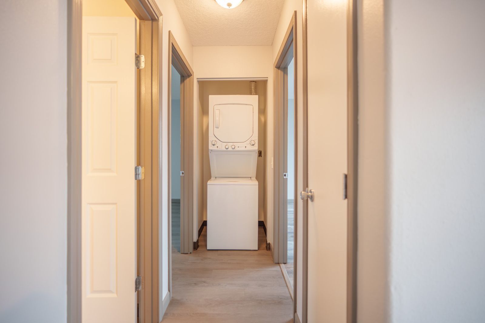 Narrow hallway with open doors and a white washer or dryer at the far end