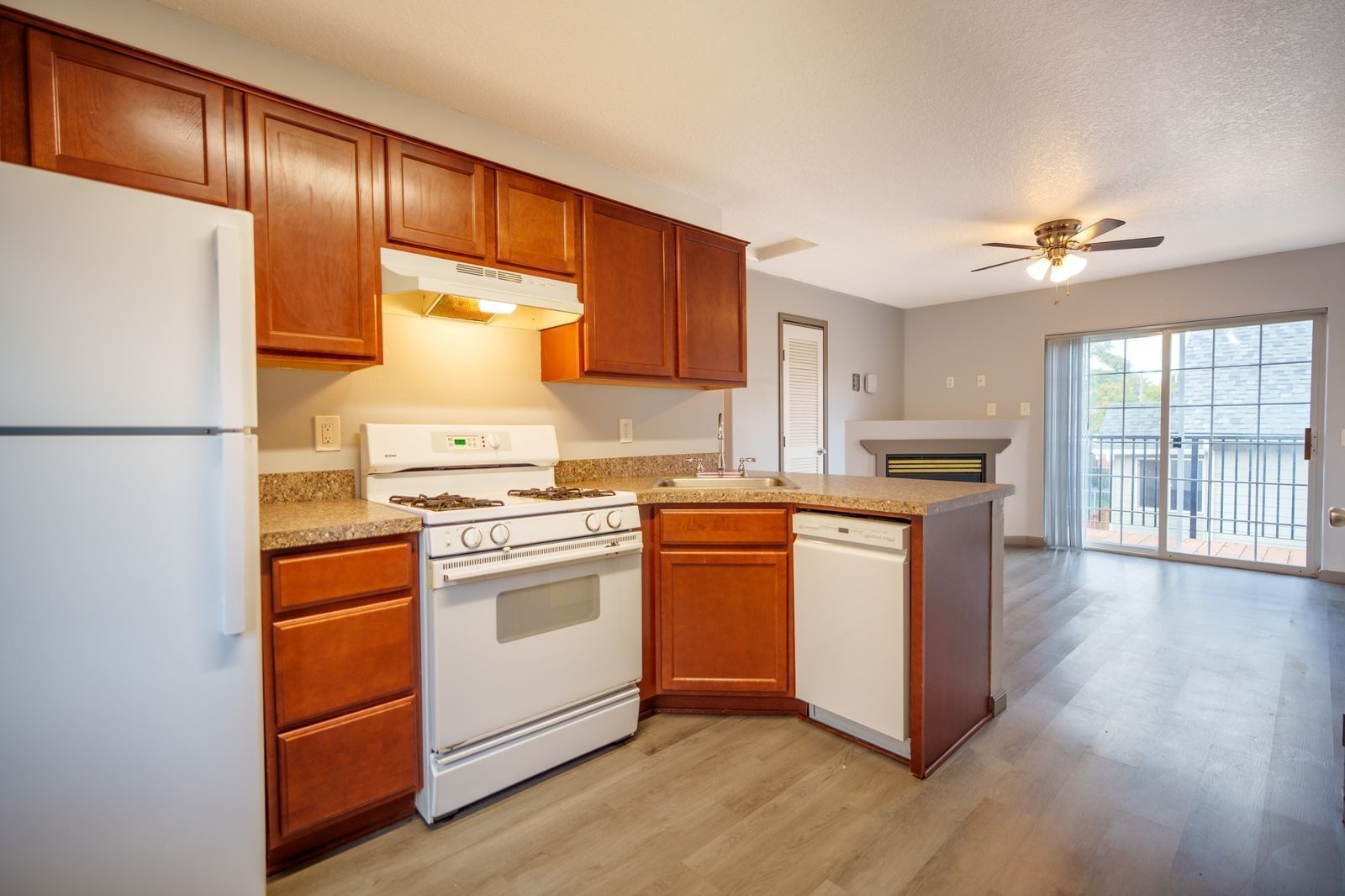 Kitchen with white appliances, wood cabinets, and an open dining area with sliding glass doors.
