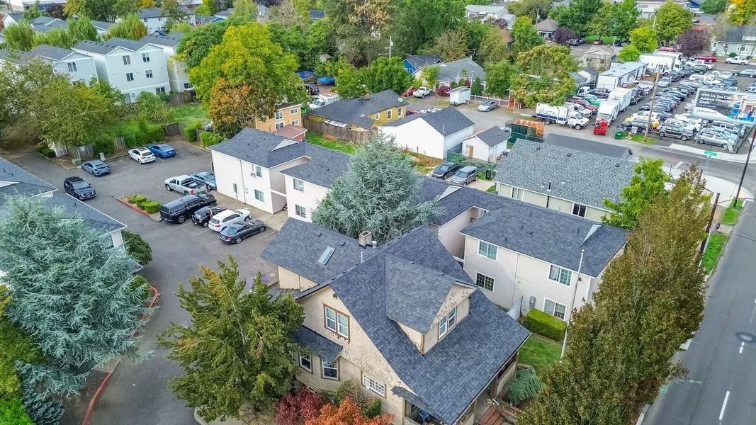 Aerial view of a suburban apartment complex with parked cars, trees, and surrounding streets