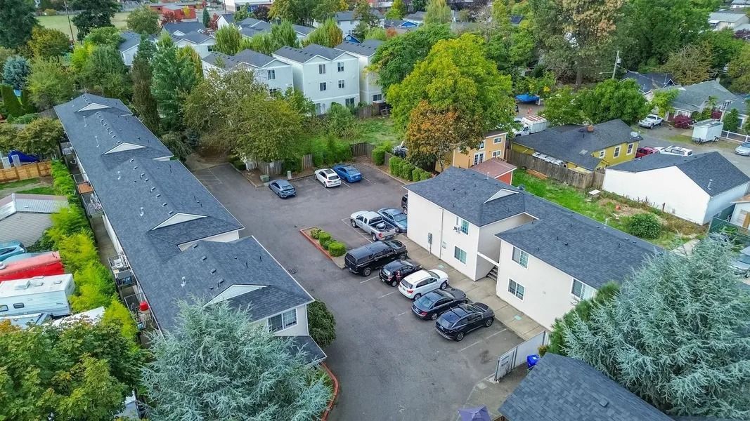 Aerial view of a parking lot beside long buildings and trees in a residential area