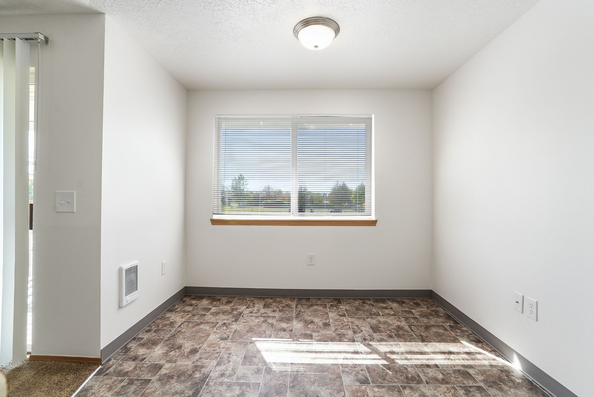 Empty white bedroom with window blinds, carpet, and ceiling light