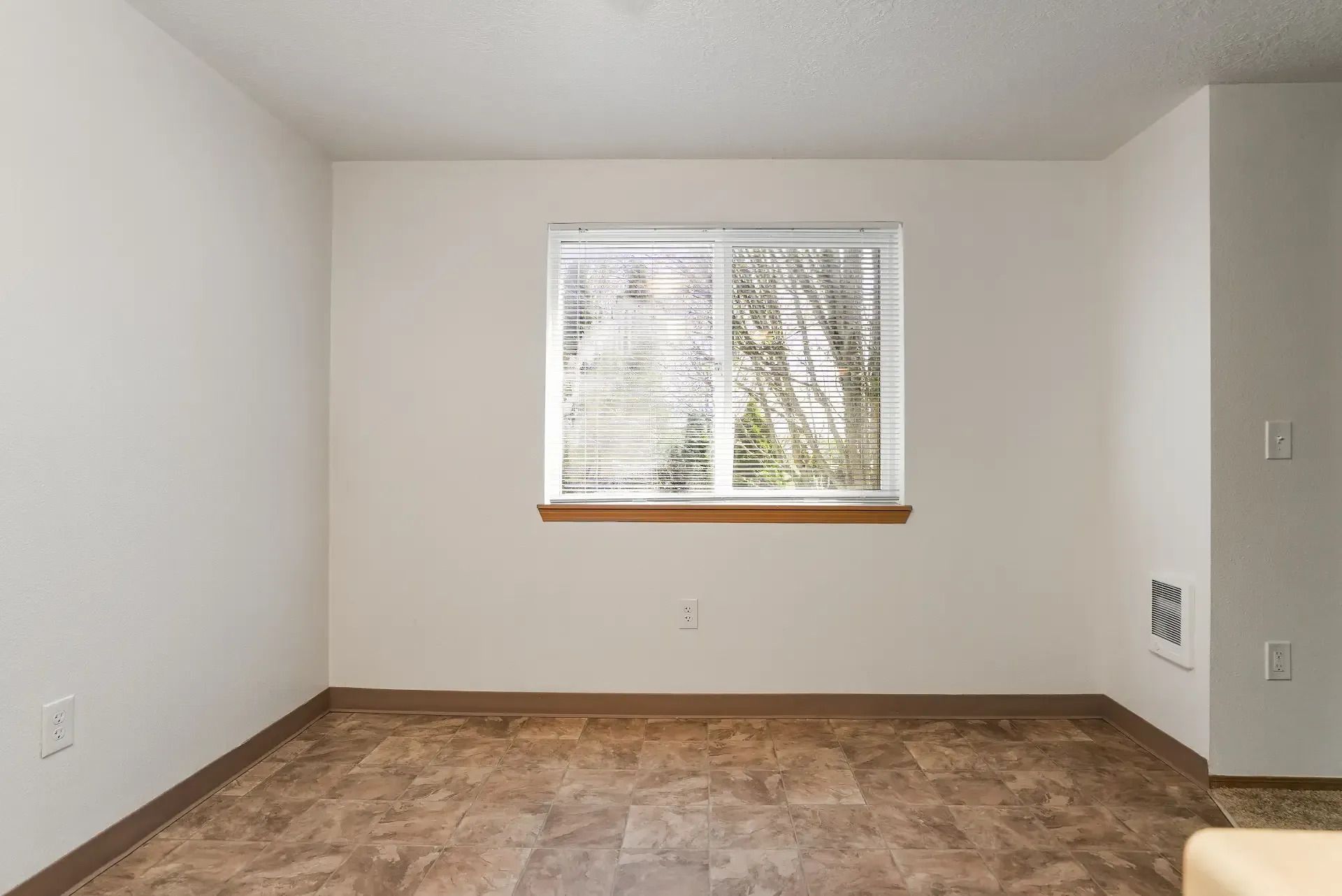 Empty carpeted room with white walls and a single window.