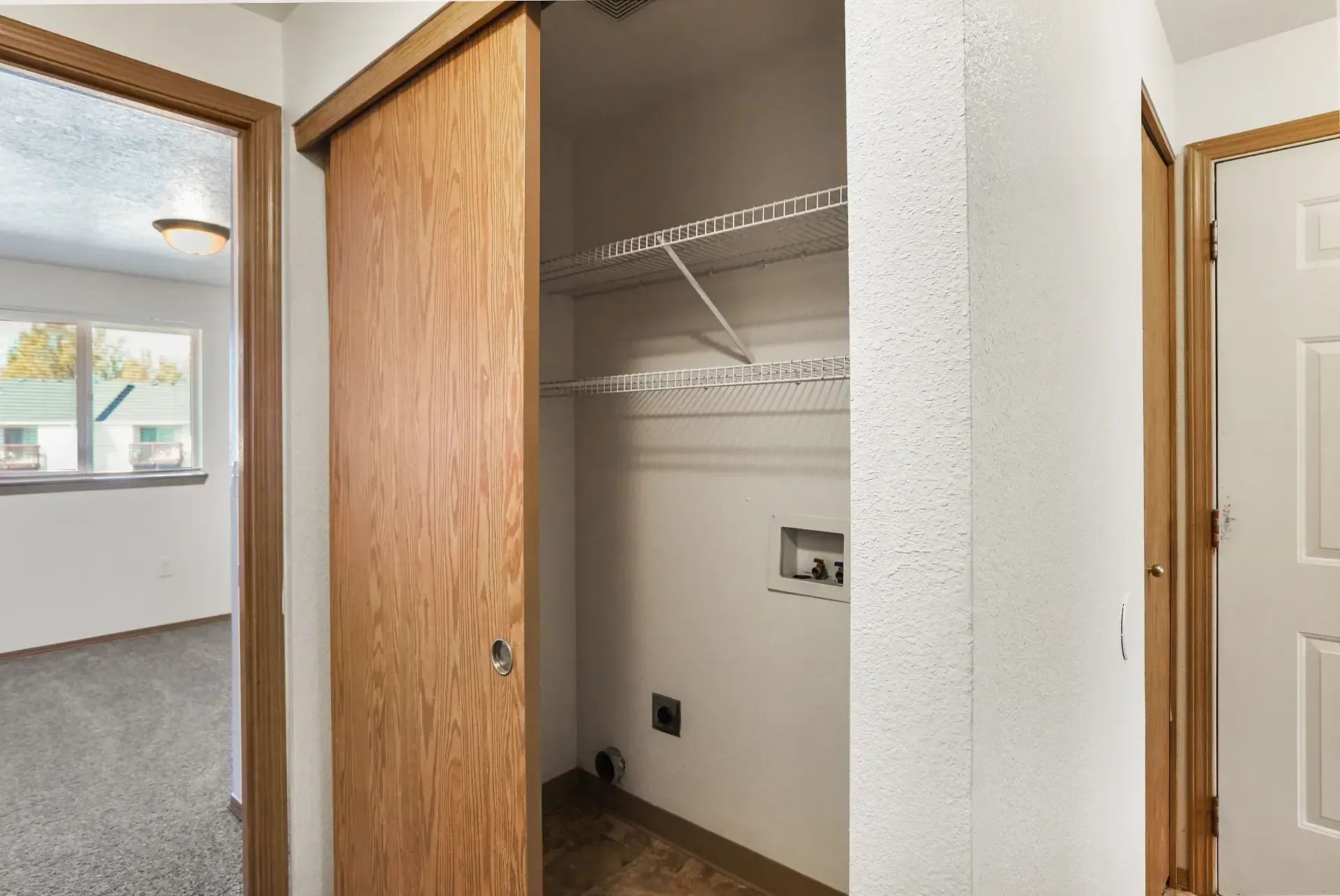 Open closet with wire shelves and sliding wood door in a carpeted hallway