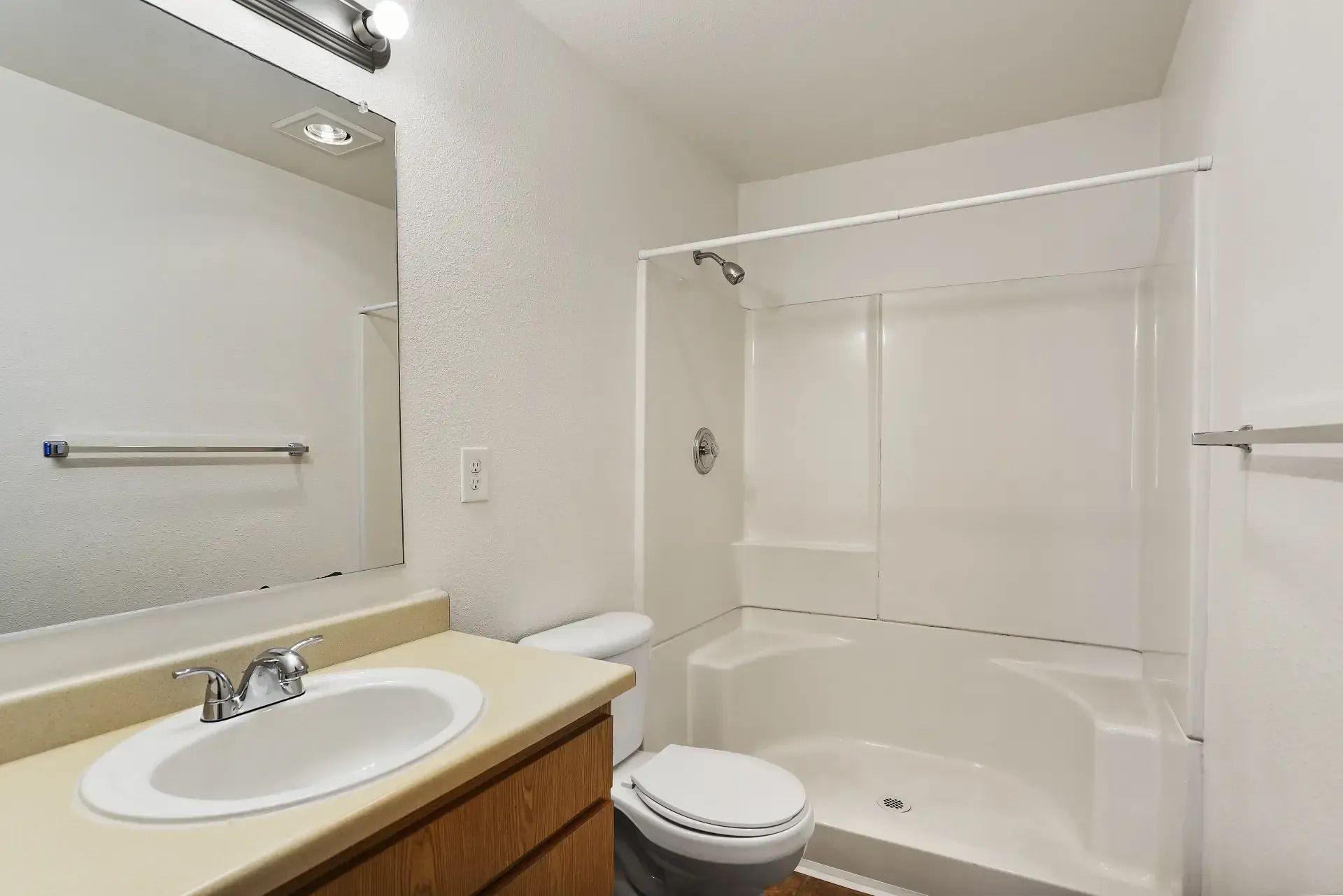 Bathroom with vanity sink, mirror, toilet, and shower-tub combo in a beige and white interior