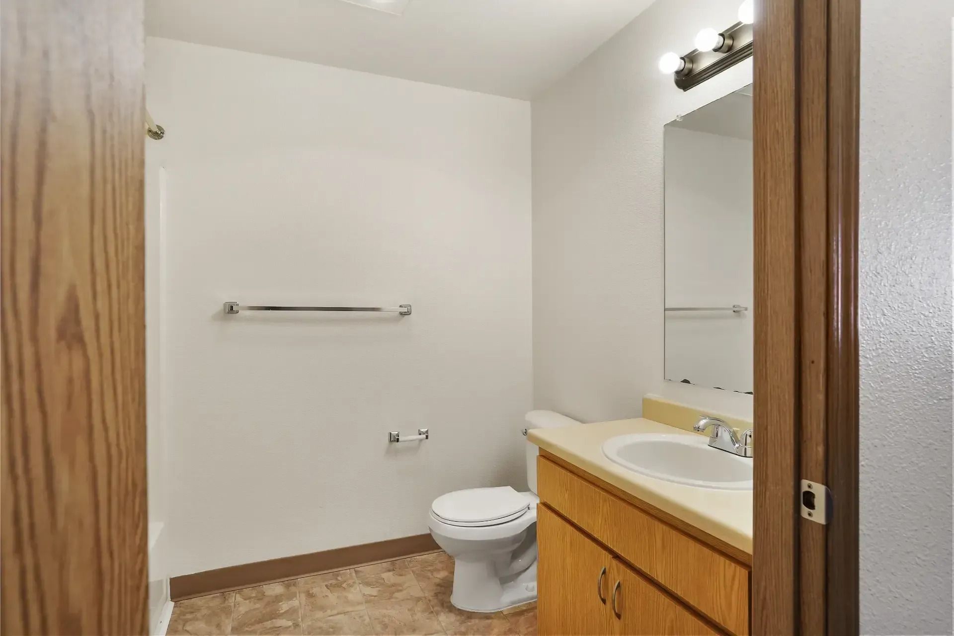 Bathroom with toilet, sink vanity, mirror, towel bar, and wood trim.