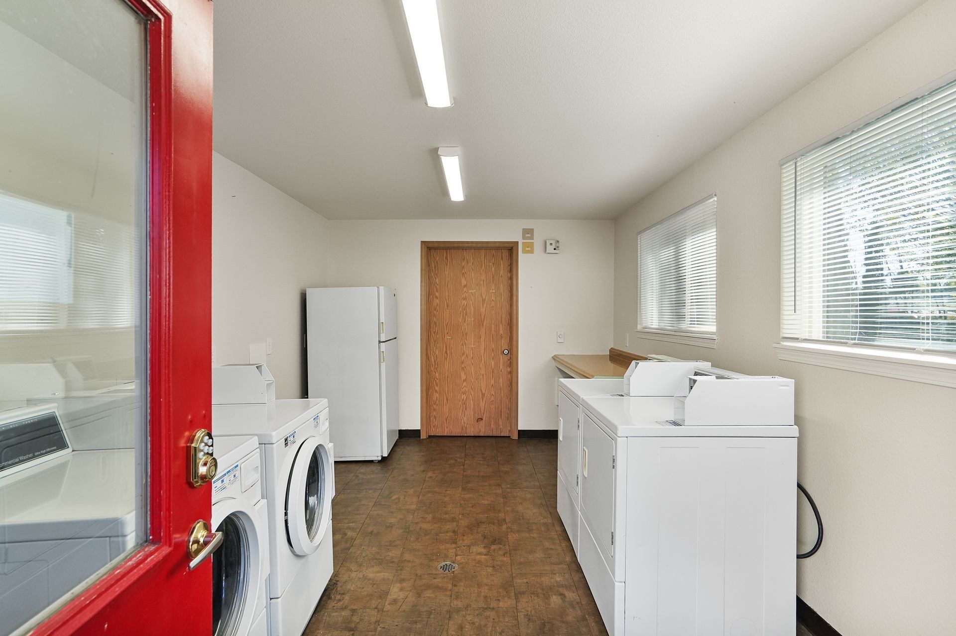 Laundry room with washer and dryer, white cabinets, windows, and a wooden door