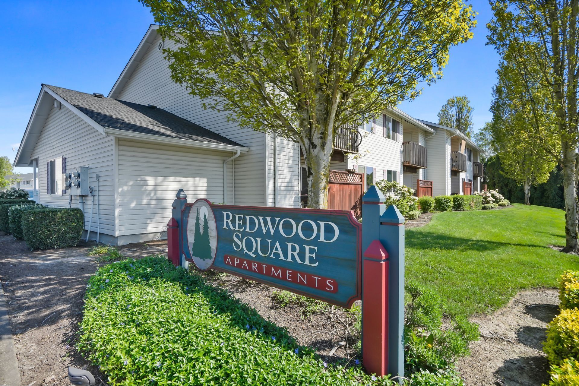 Redwood Square sign in front of apartment buildings and green landscaping on a sunny day