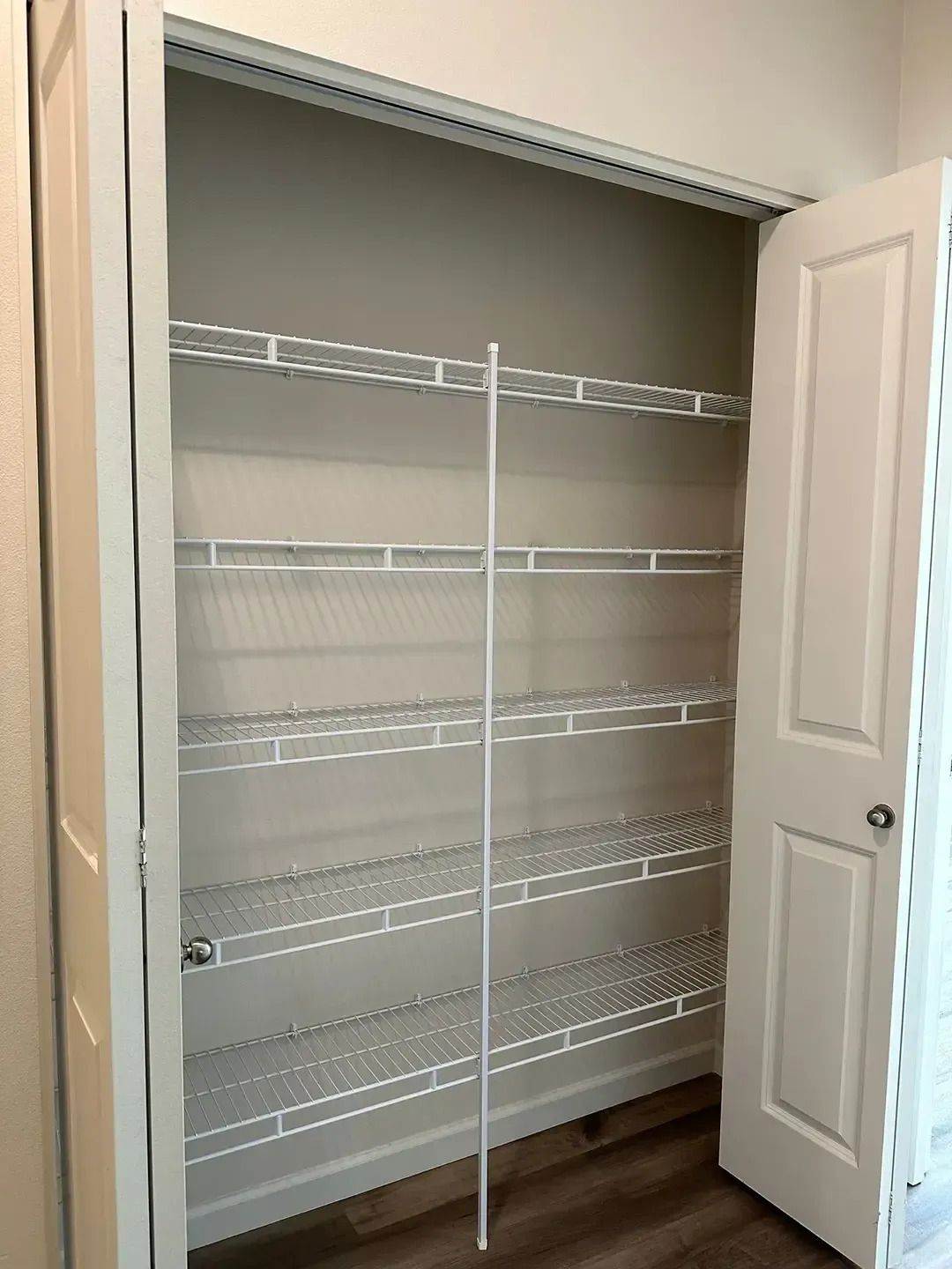 Open closet with white wire shelving and a partially open door, showing empty storage space.