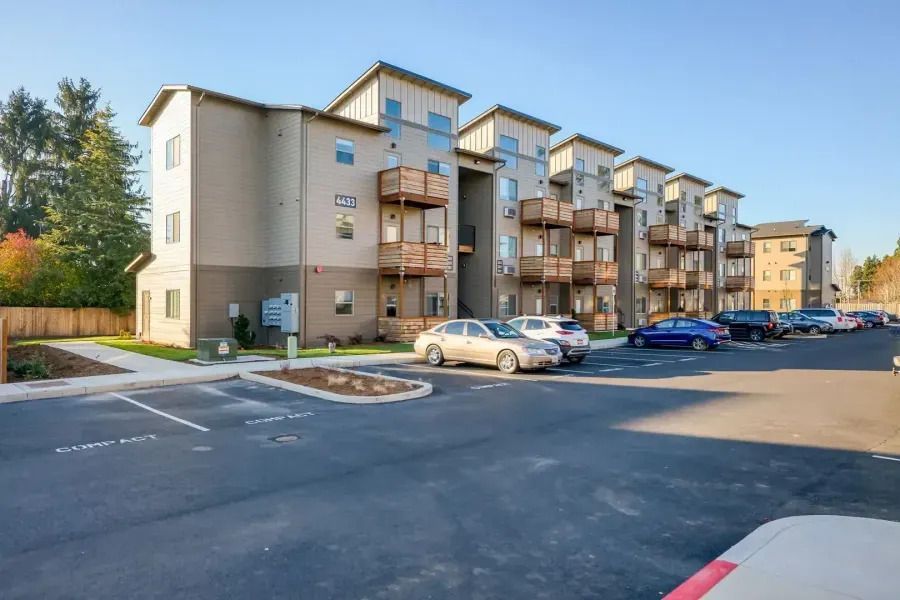 Apartment complex parking lot with parked cars and beige buildings at sunset