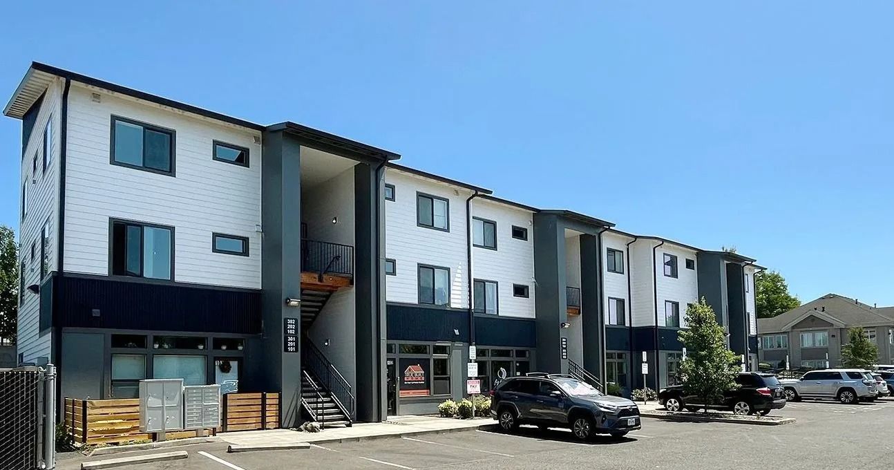 Modern apartment building exterior with parked cars and a clear blue sky