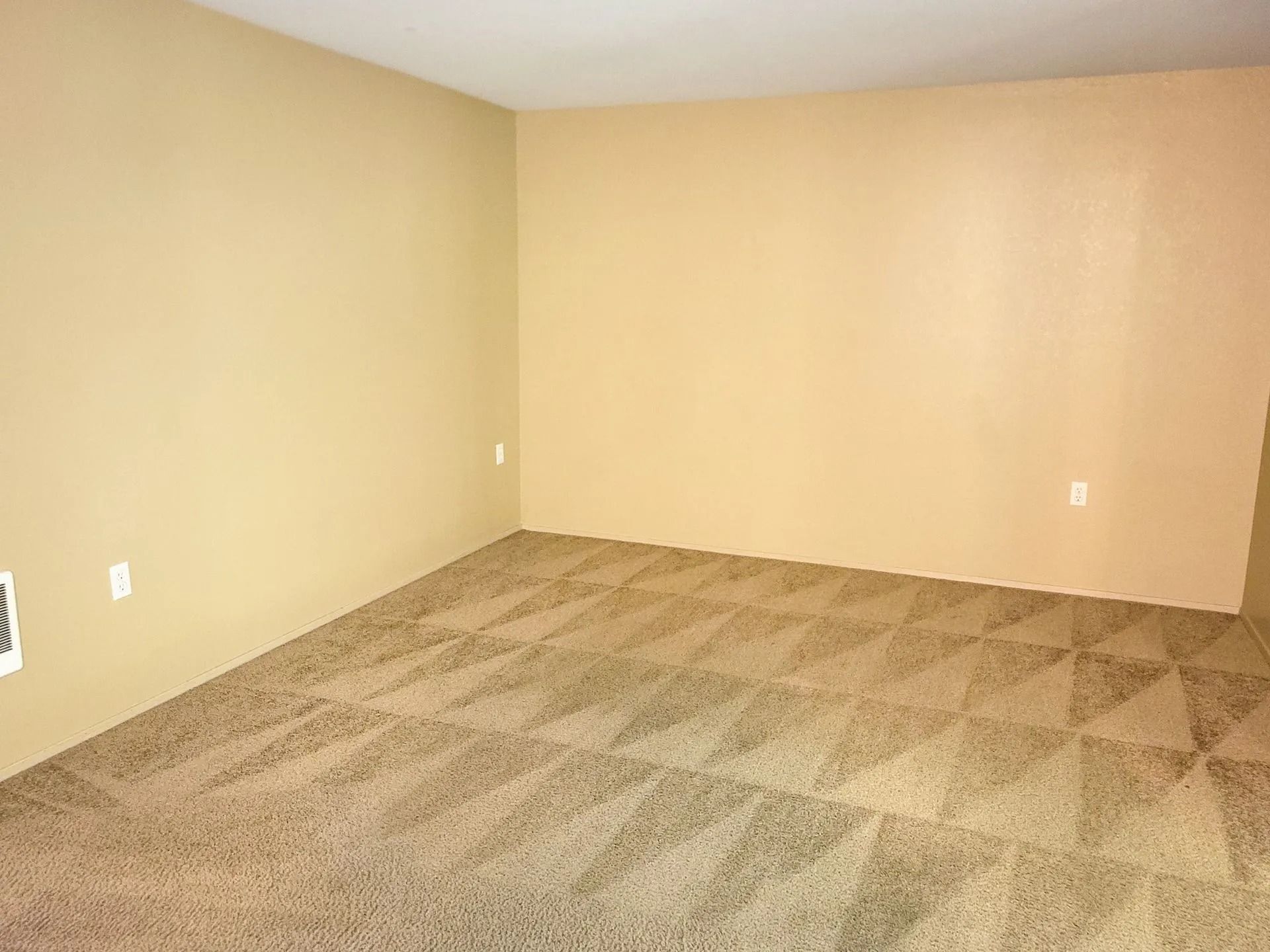 Empty beige room with tan carpet and plain walls