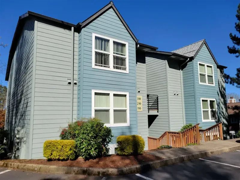 Light blue townhouse with white trim and small front garden on a sunny day