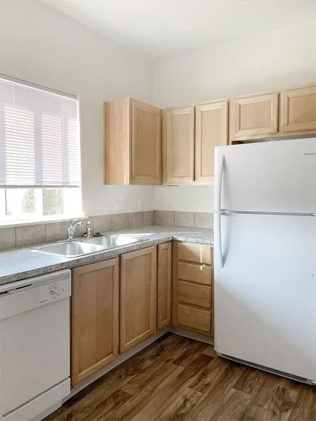 Small kitchen with light wood cabinets, white appliances, and a window over the sink.