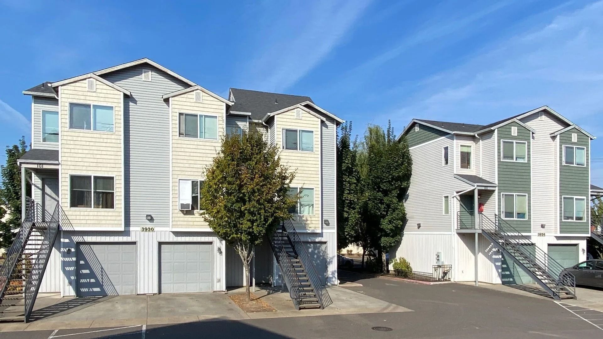 Two-story apartment buildings with garages and balconies under a clear blue sky