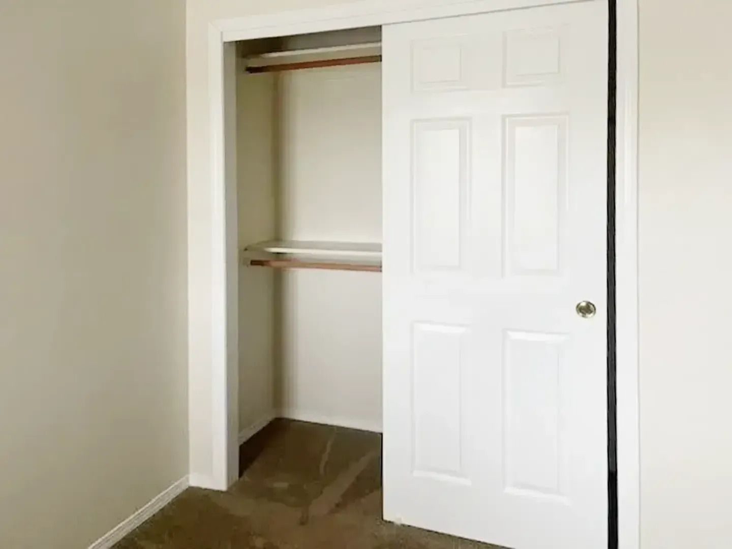 Open closet with white sliding door in a beige room