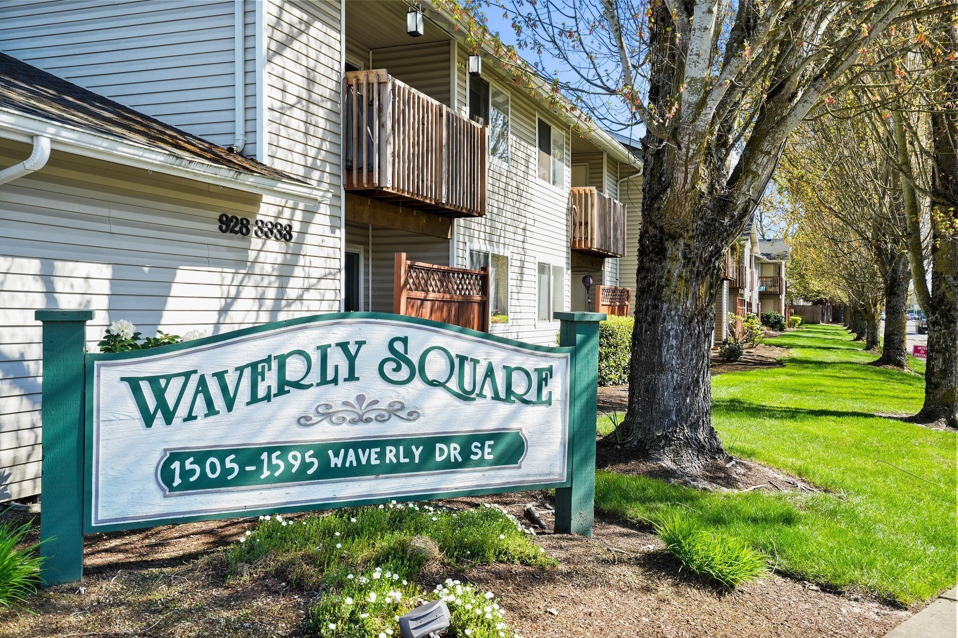 Waverly Square sign beside white apartment buildings and trees on a sunny day