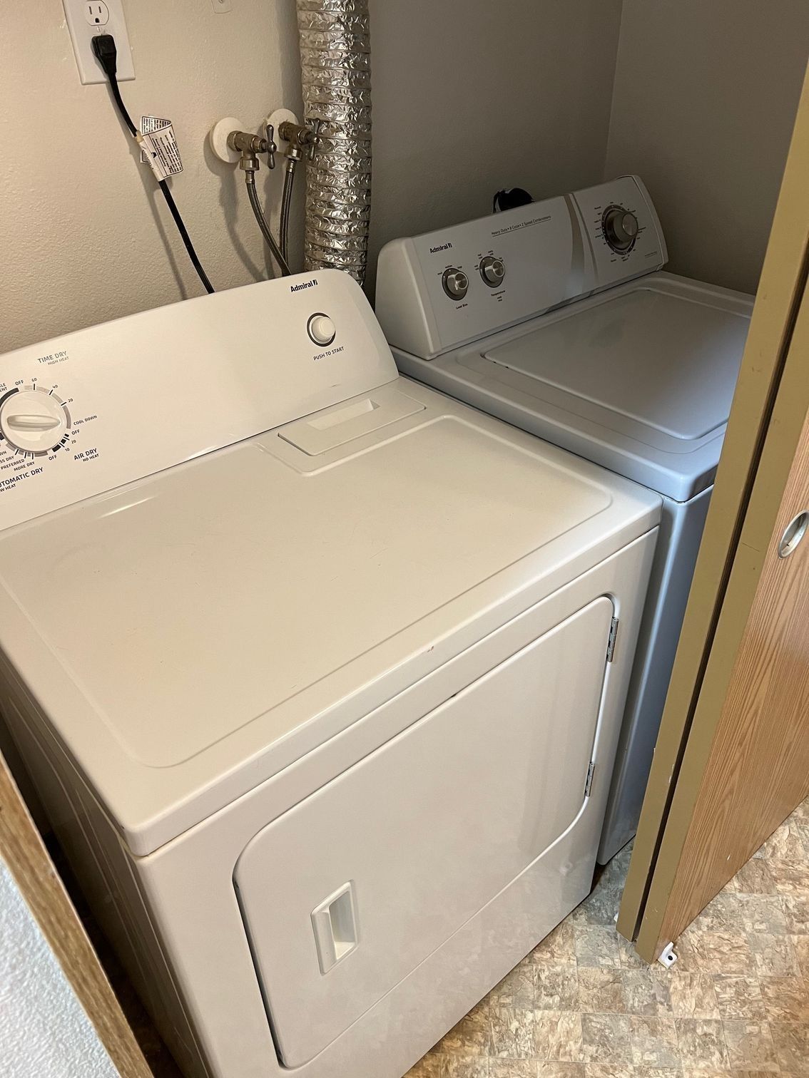 Laundry room with a white washer and dryer side by side in a tight closet space