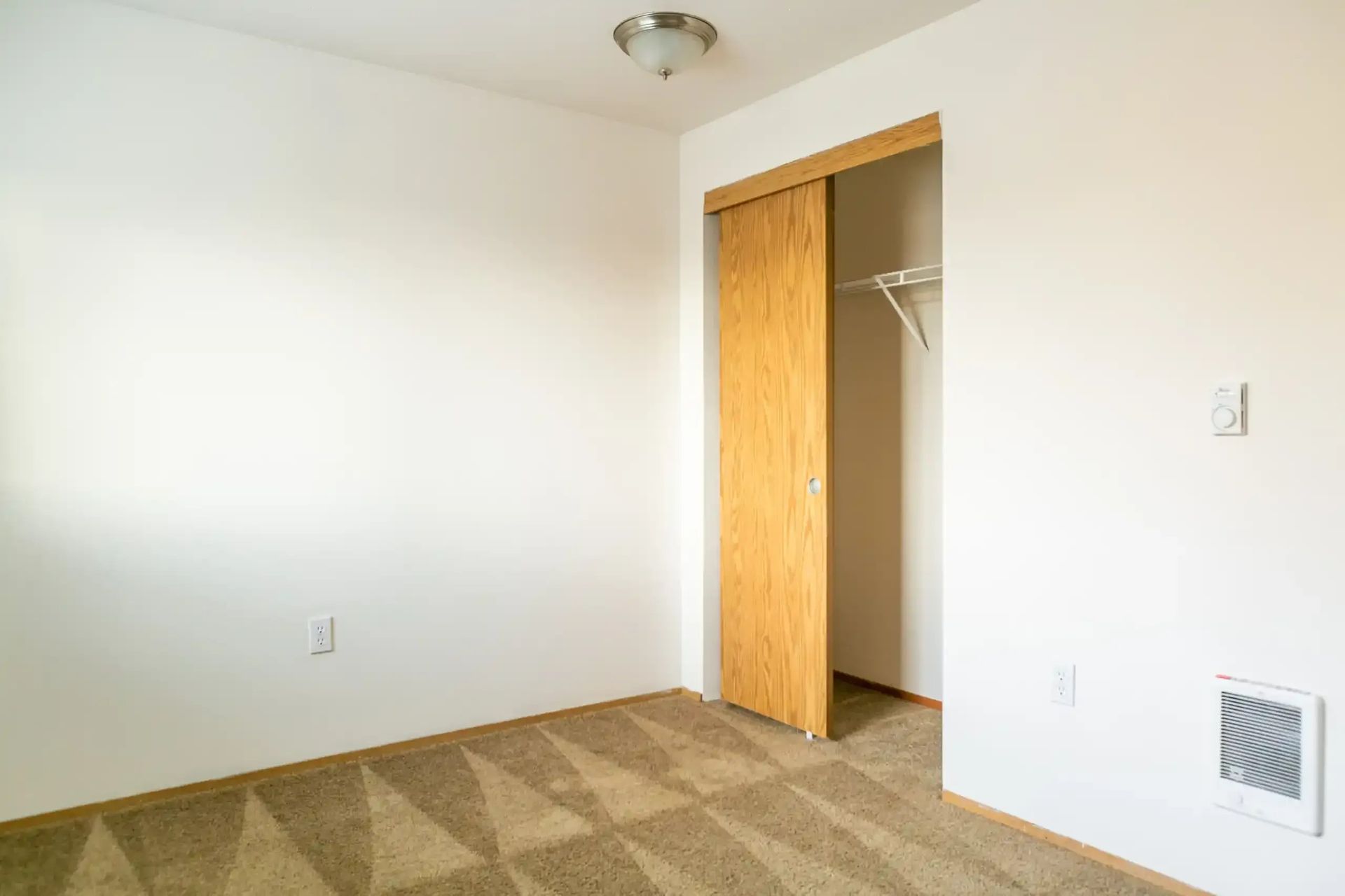 Empty beige bedroom with open closet and white walls