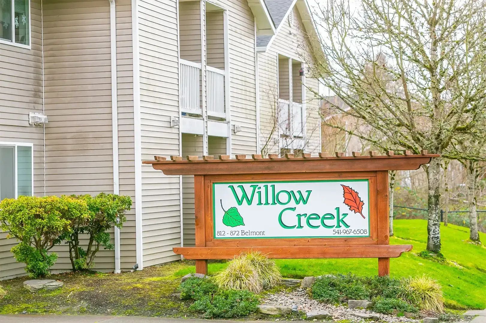 Willow Creek apartment sign beside a beige building and green shrubs