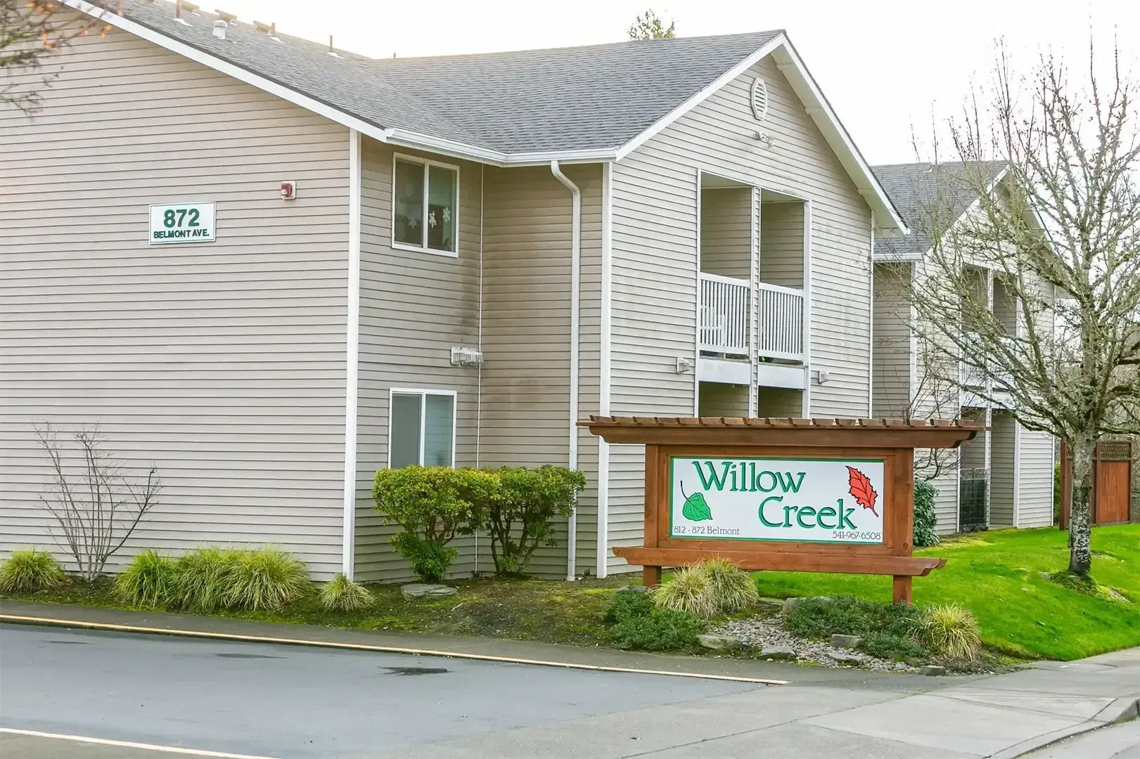Apartment building entrance with a Millay Creek sign and landscaped lawn