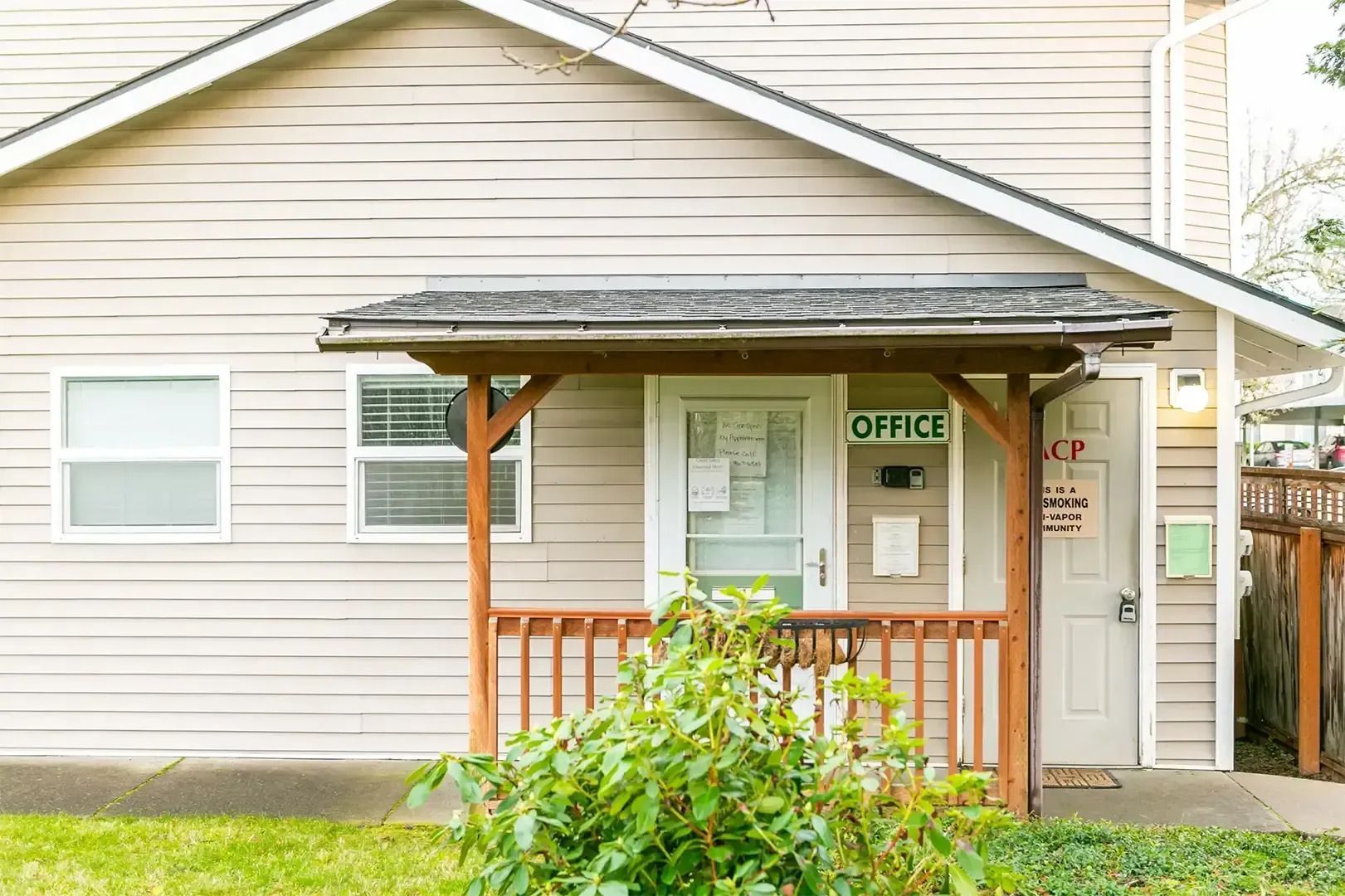 Small office entrance with porch, windows, and an “OFFICE” sign on a beige building
