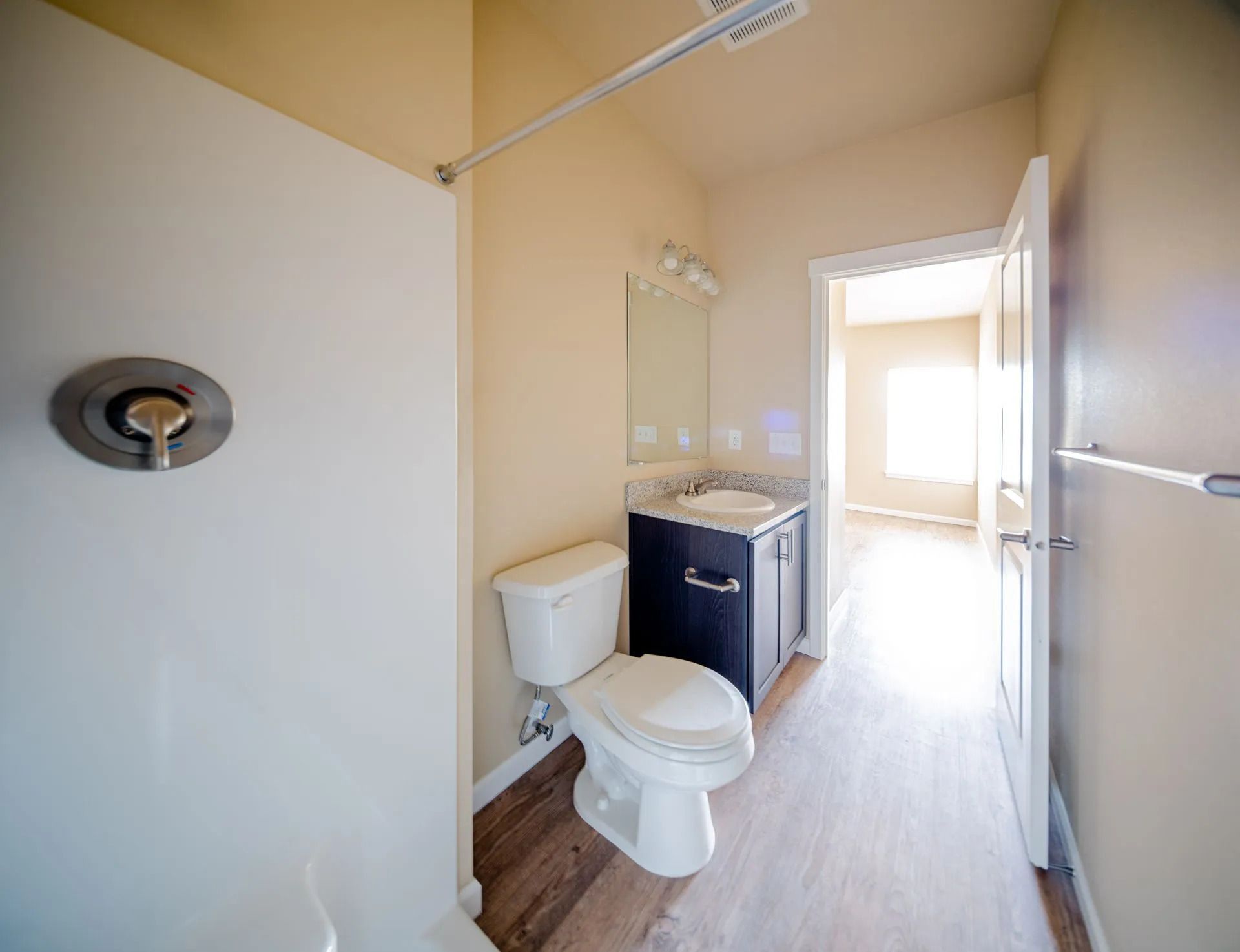 Small bathroom with toilet, vanity sink, and shower stall, in white and beige tones.