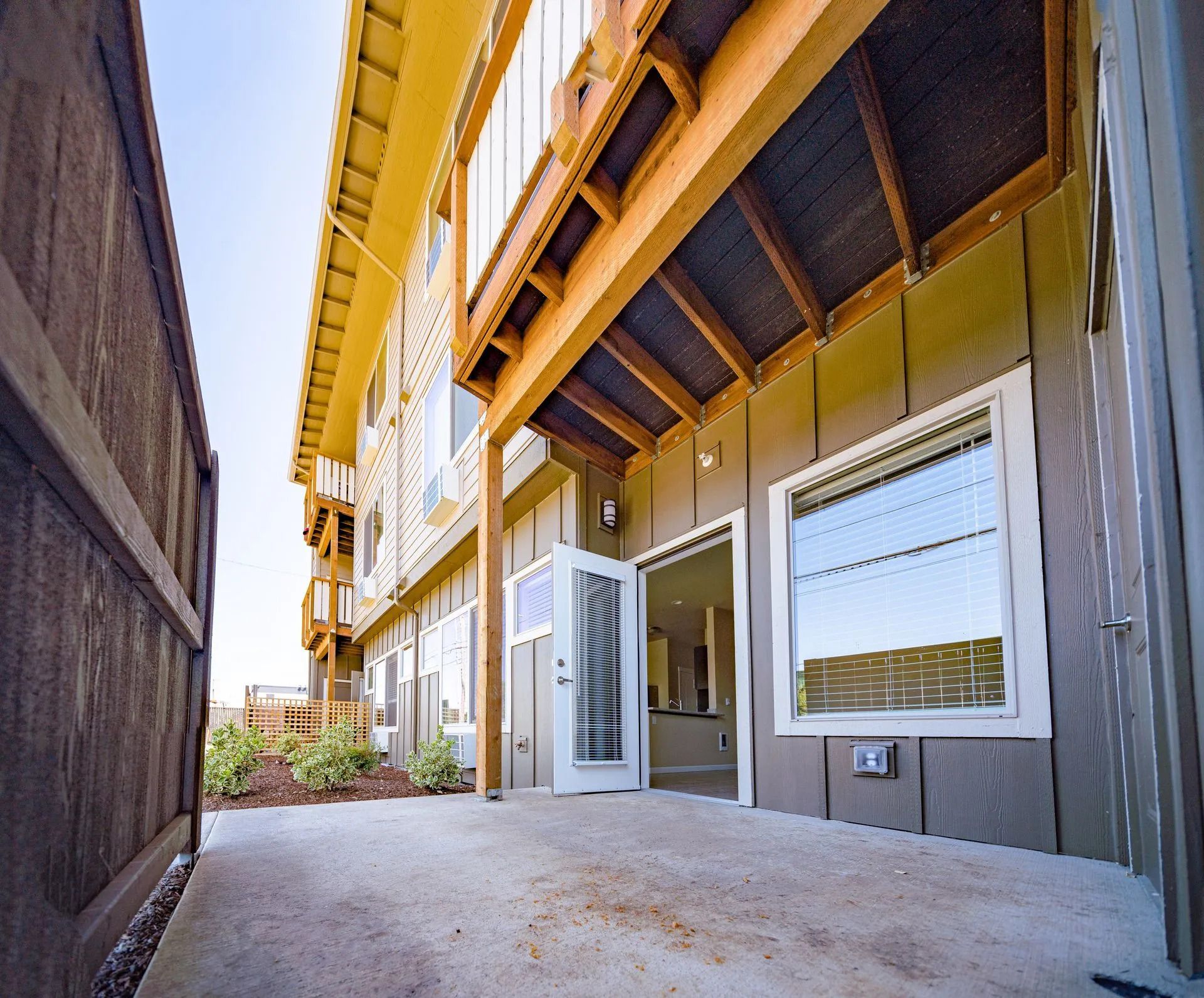 Back patio with open white door, white-framed windows, and yellow overhang on a house exterior.