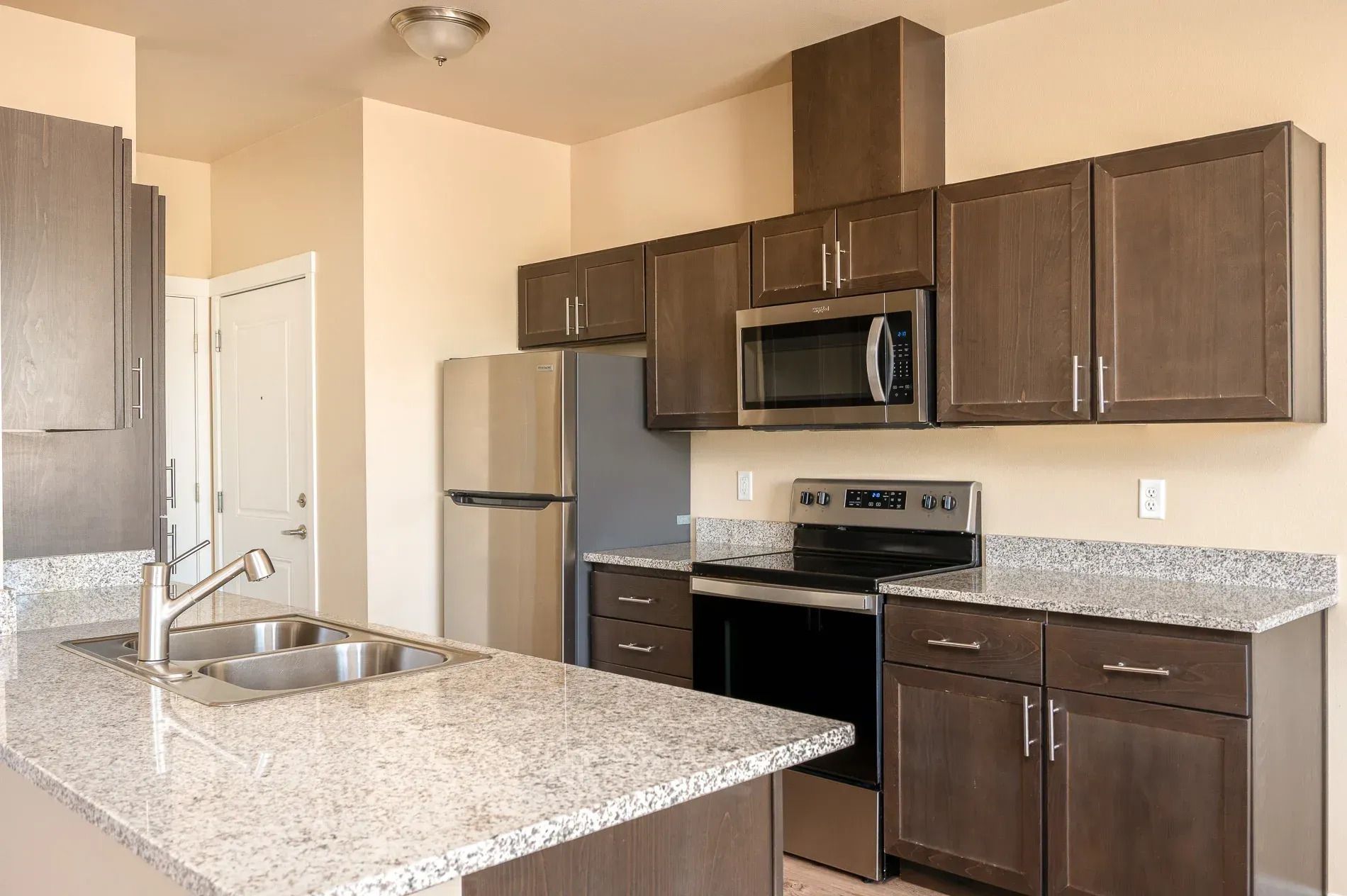 Modern kitchen with stainless steel appliances, dark wood cabinets, and granite countertops