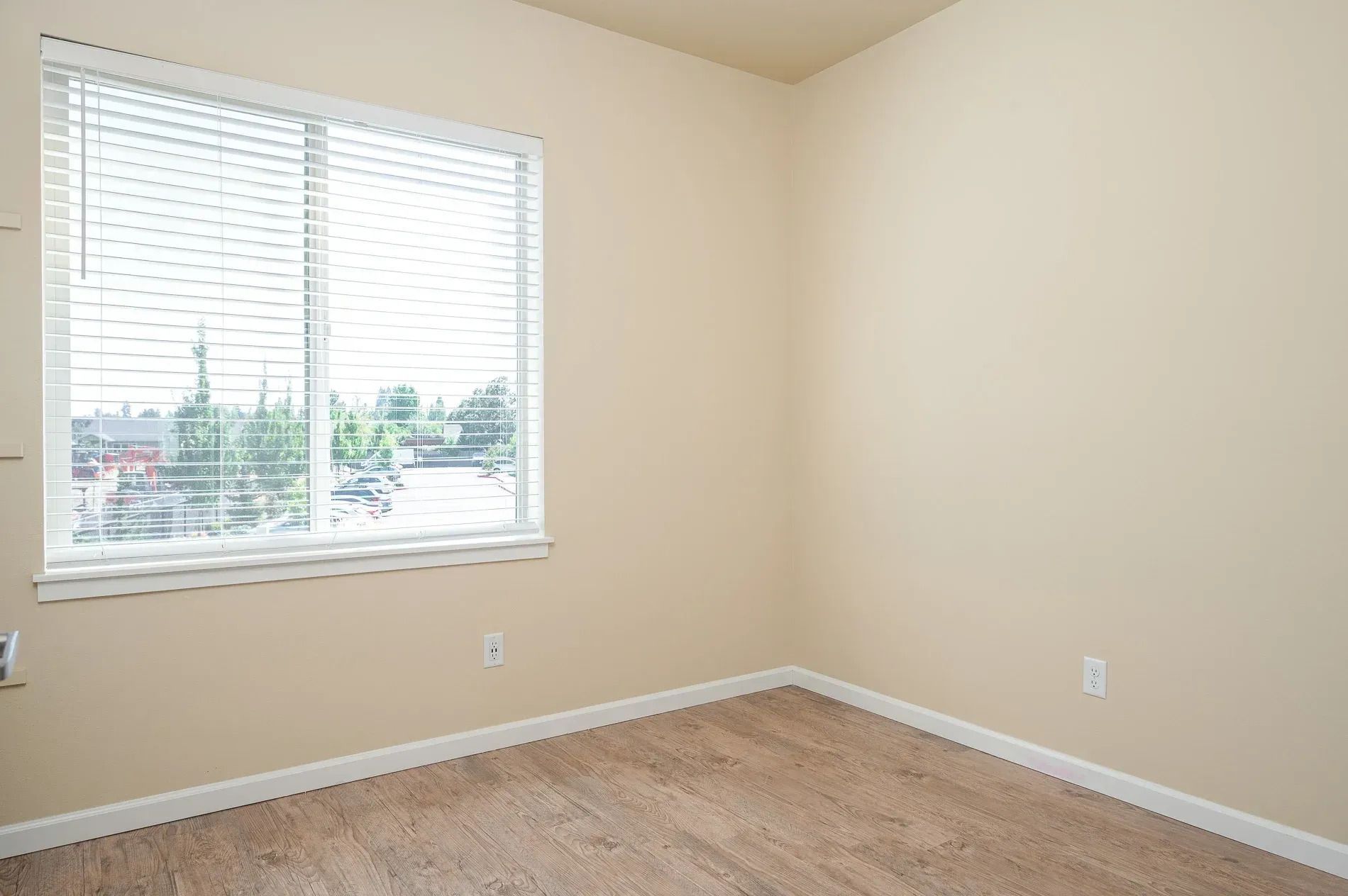 Empty beige bedroom with window blinds and carpeted floor