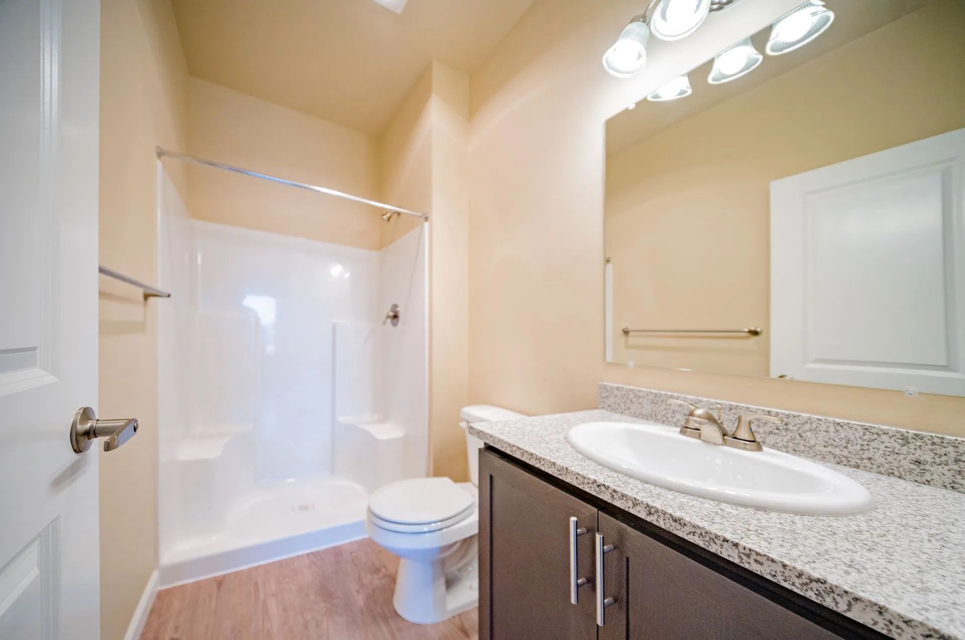 Bright beige bathroom with shower, toilet, sink vanity, and large mirror