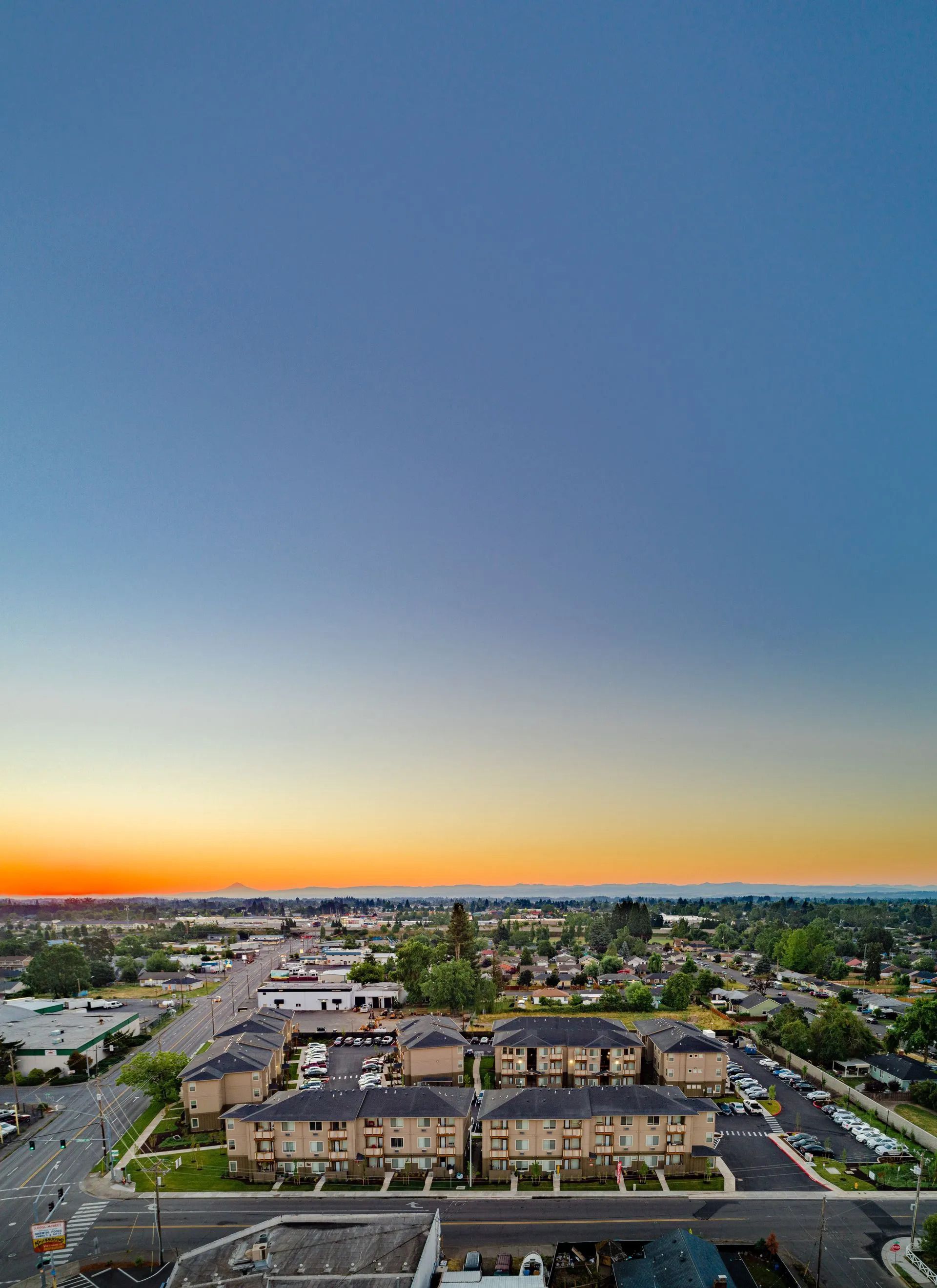 Aerial view of a suburban neighborhood at sunset under a blue-orange sky