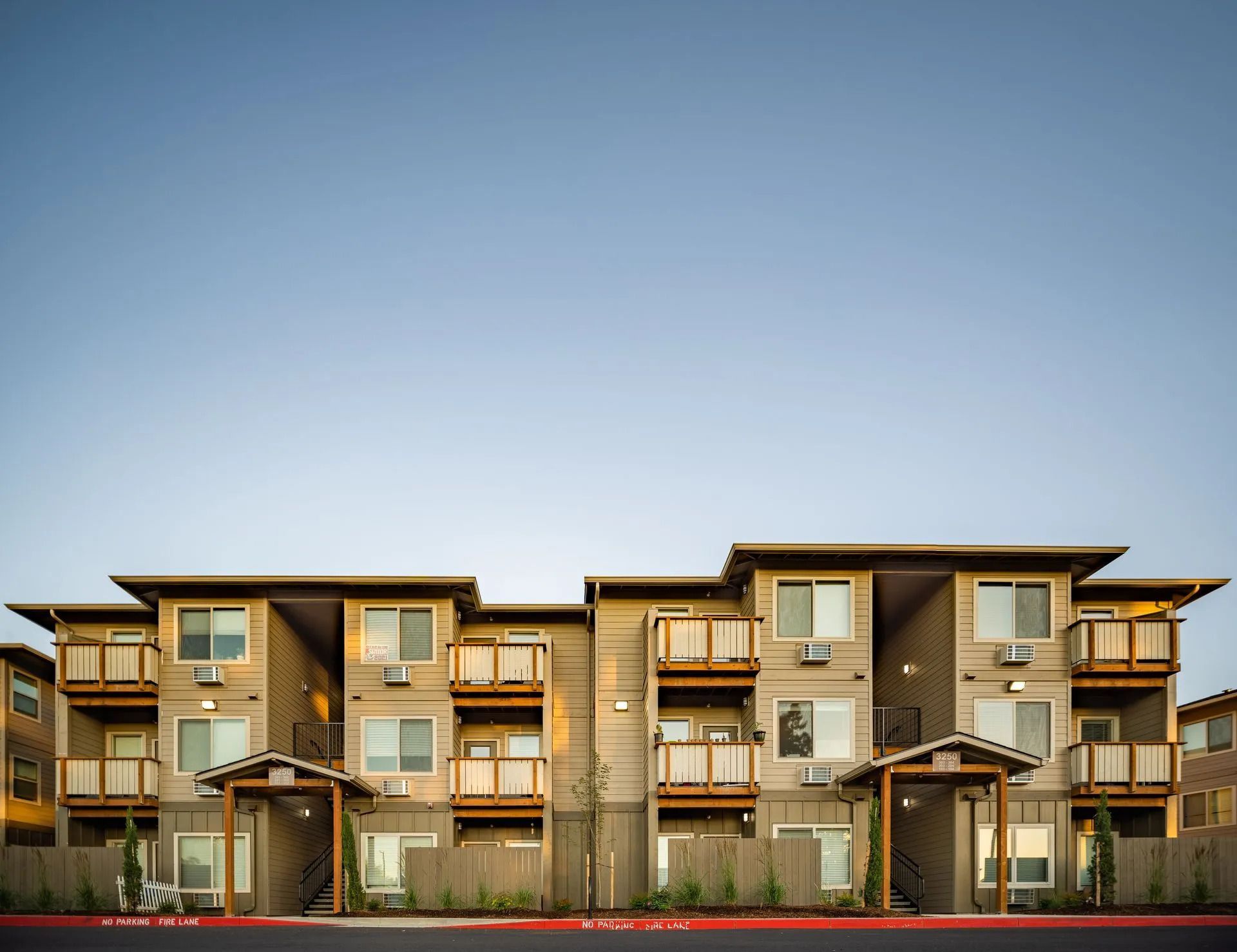 Modern two-story apartment buildings with balconies under a clear blue sky