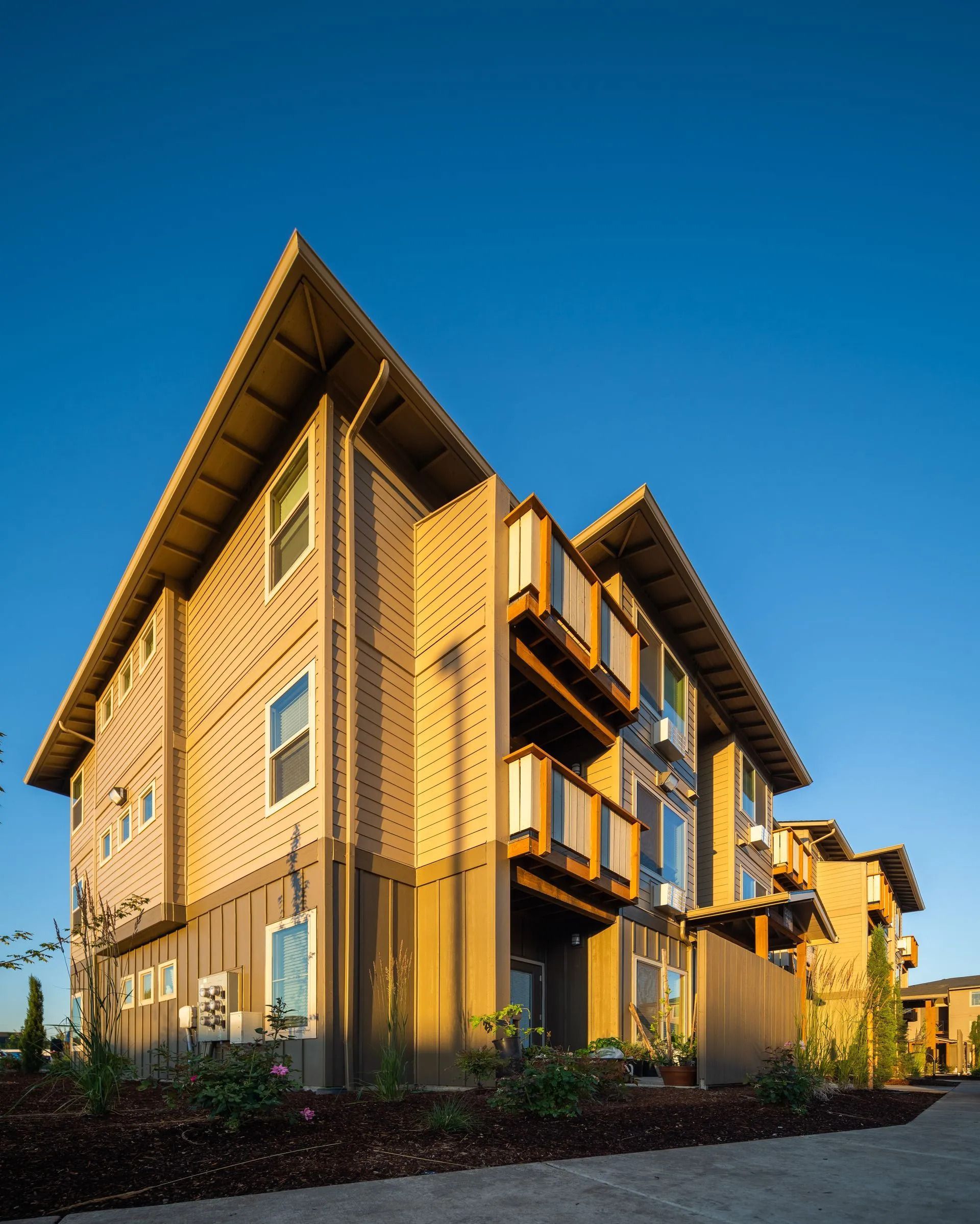 Modern tan apartment building with balconies under a clear blue sky