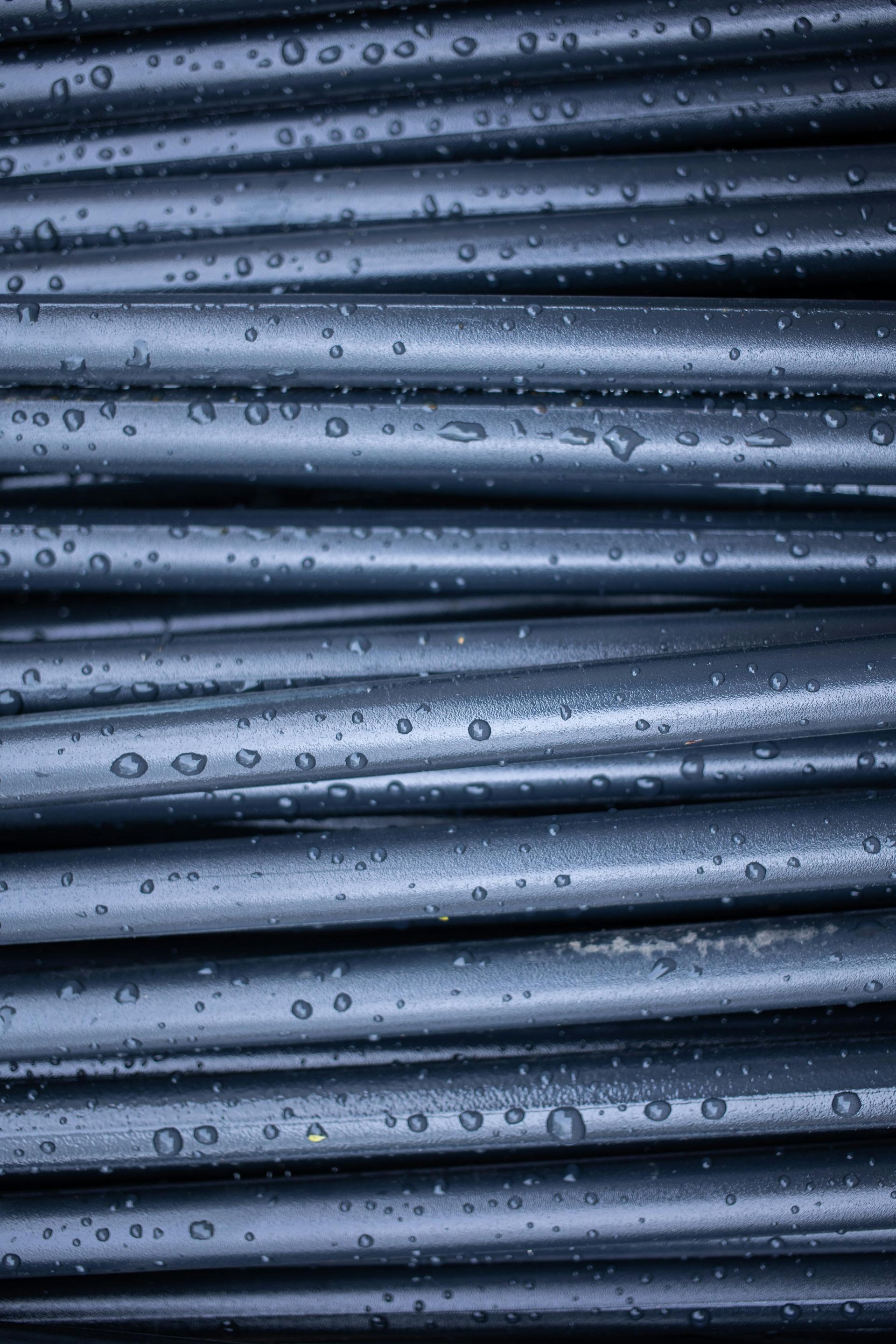 Close-up of stacked wet drainage pipes with water droplets and horizontal ridges