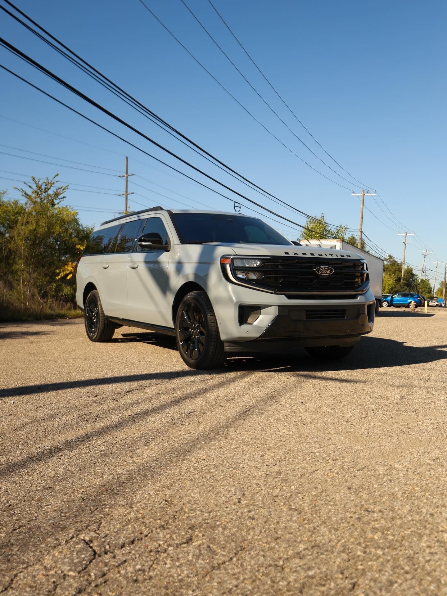 Gray SUV parked on a cracked asphalt road under a clear, sunny sky.