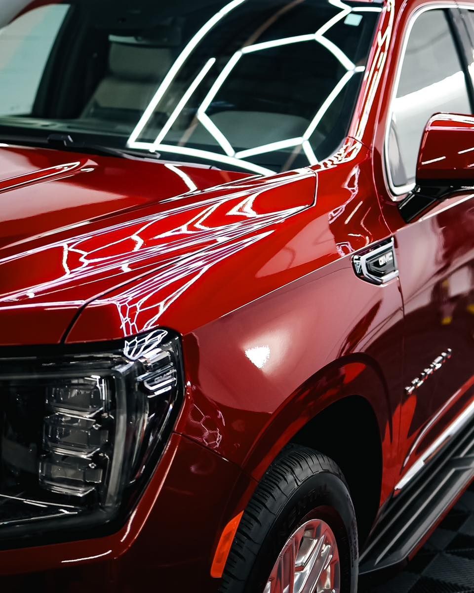 Red pickup truck with glossy paint, showing the front side and windshield reflections.