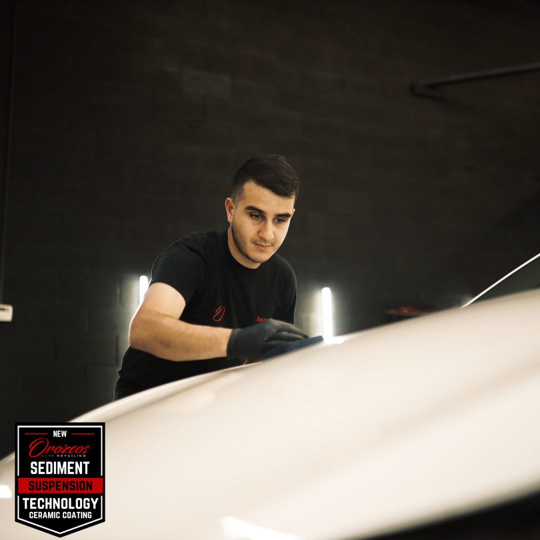 A man in a black shirt is polishing a white car