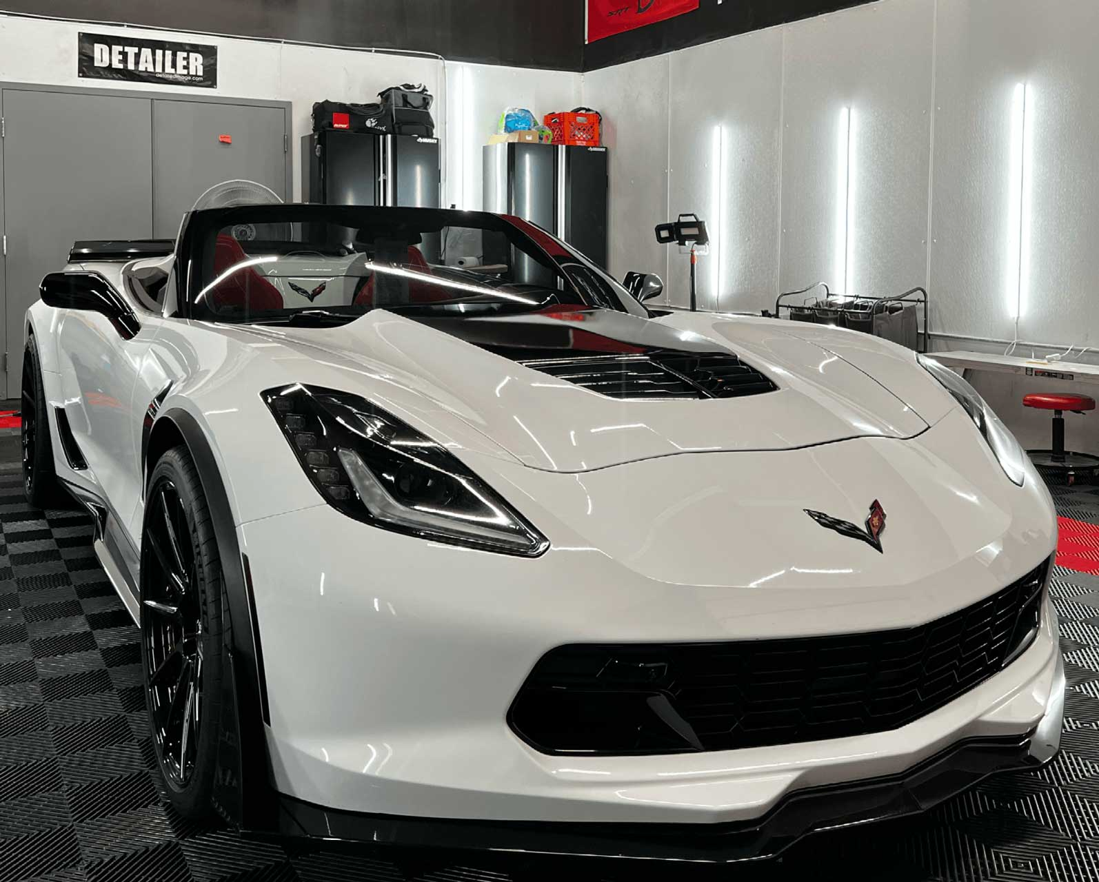 A white corvette convertible is parked in a garage.