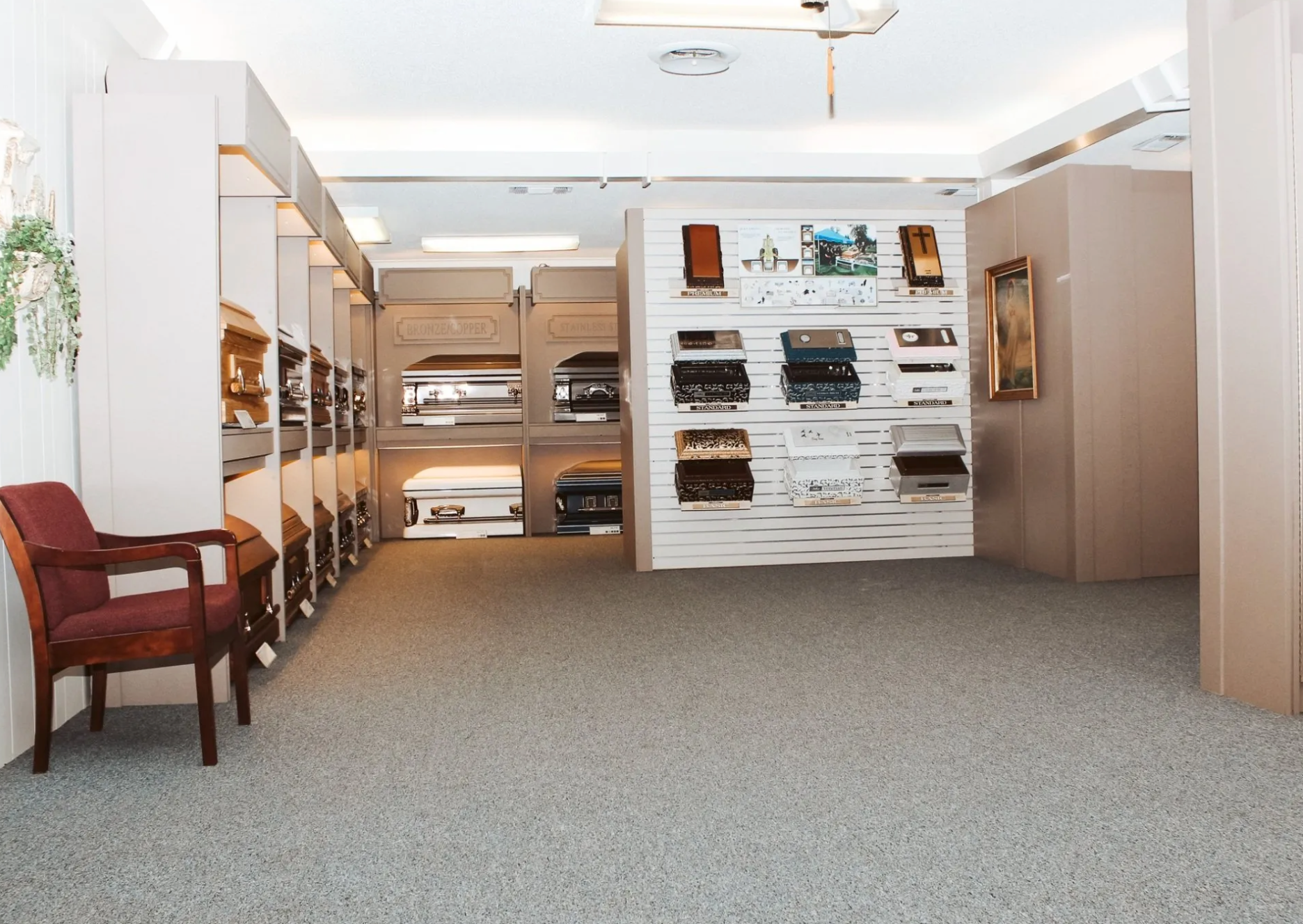 Spacious carpeted room with shelves, display racks, and a wooden chair under bright ceiling lights