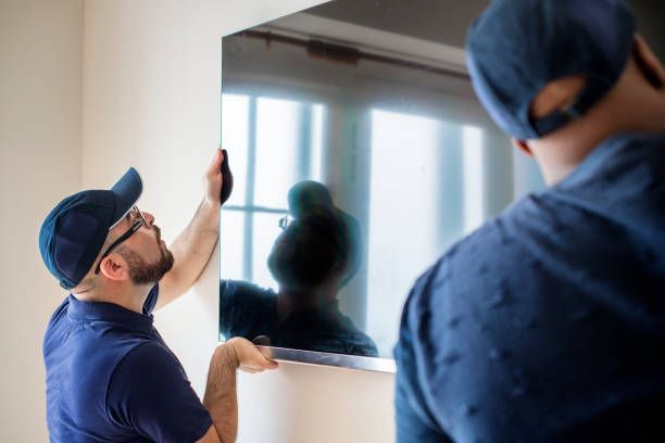 A man is installing a flat screen tv on a wall.