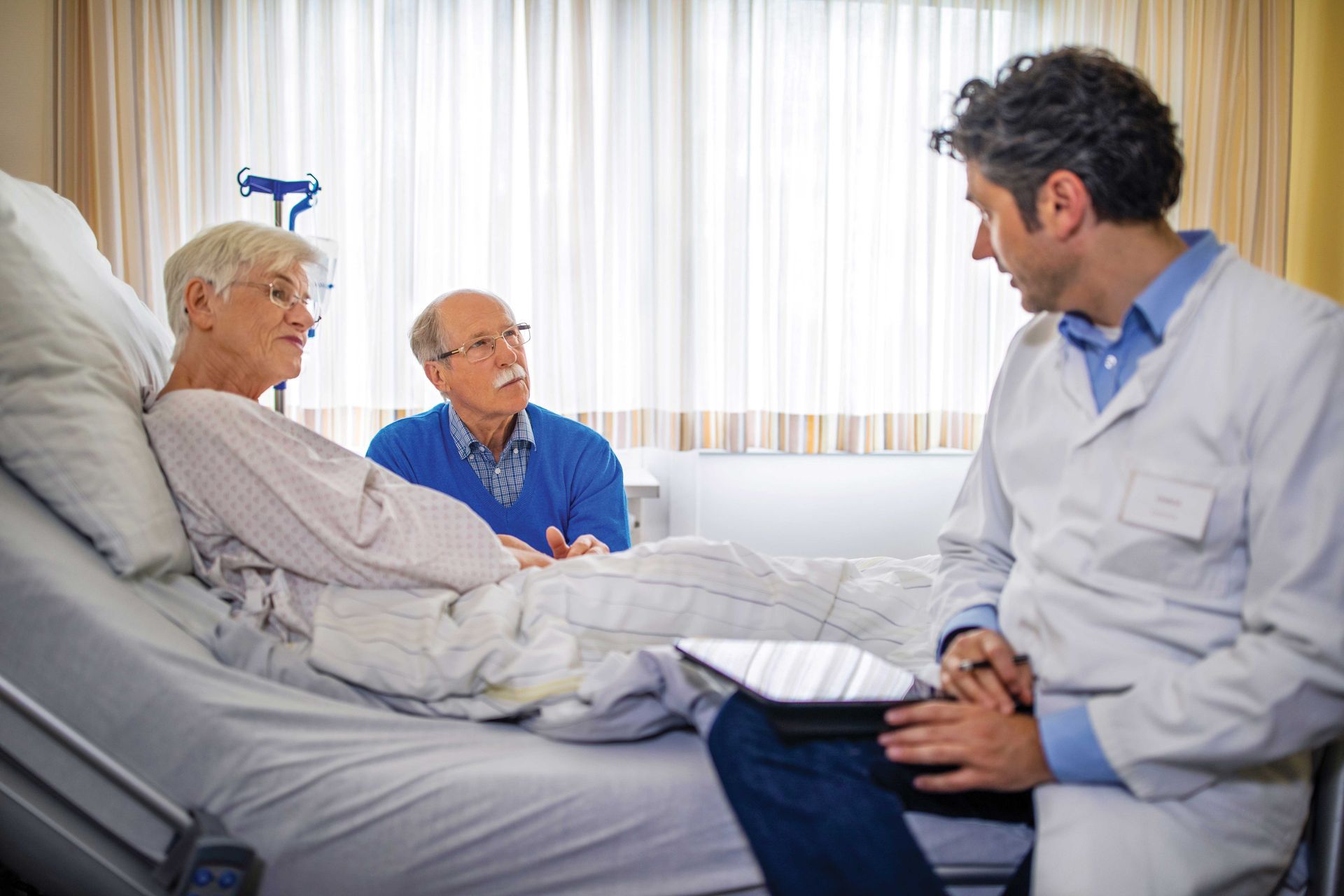 A doctor is talking to a patient in a hospital bed.