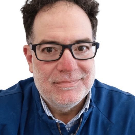 Man with glasses smiles, wearing blue jacket.