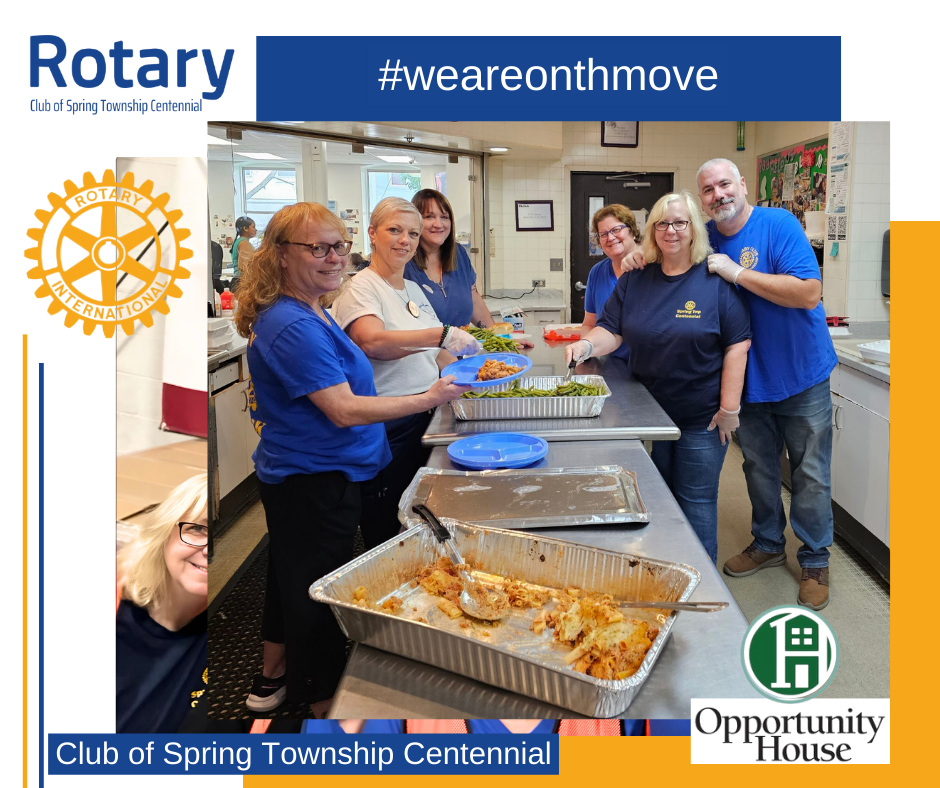 A group of people are standing around a table with trays of food.