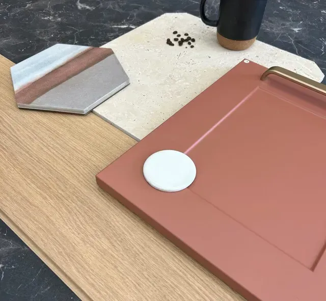 Bureau avec un dossier rose, un palet blanc circulaire, une carte à rayures grises et un gobelet noir sur une surface en bois clair.