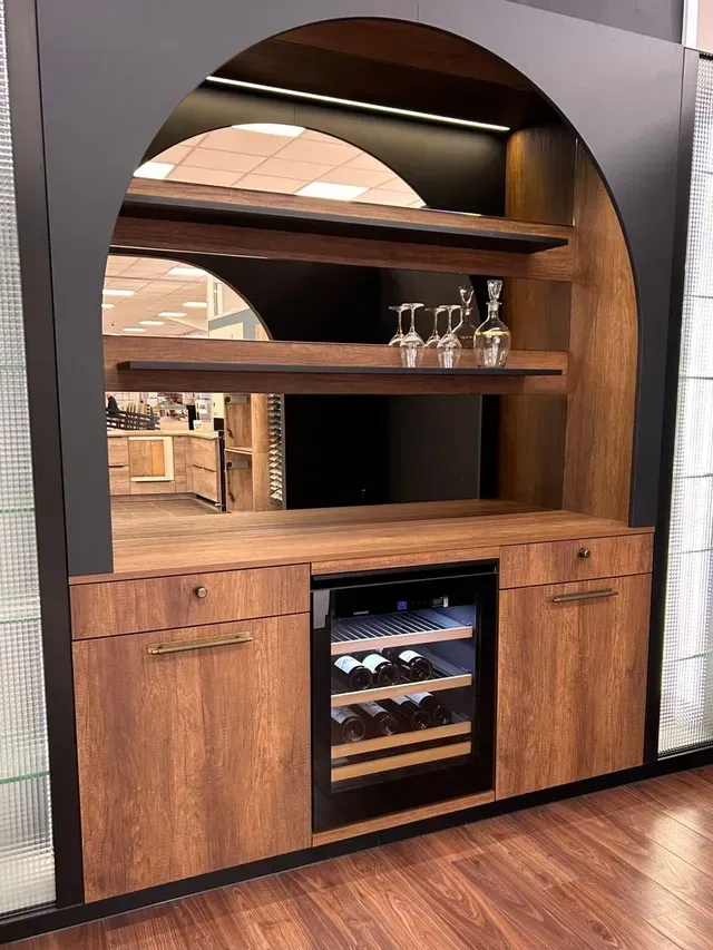 Meuble bar intégré en noyer avec cadre noir arqué, étagères, cave à vin et parquet.