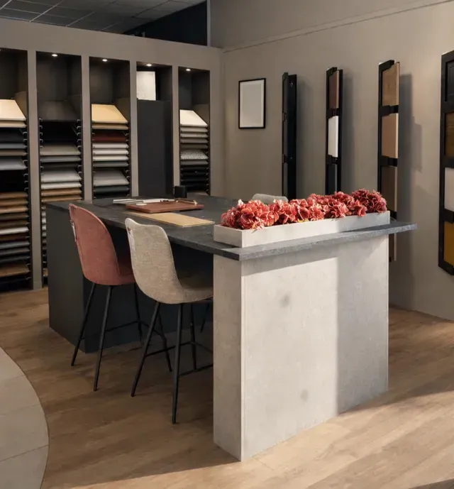 Showroom moderne avec table en béton, chaises en velours, étagères de tissus pliés et centre de table floral rouge