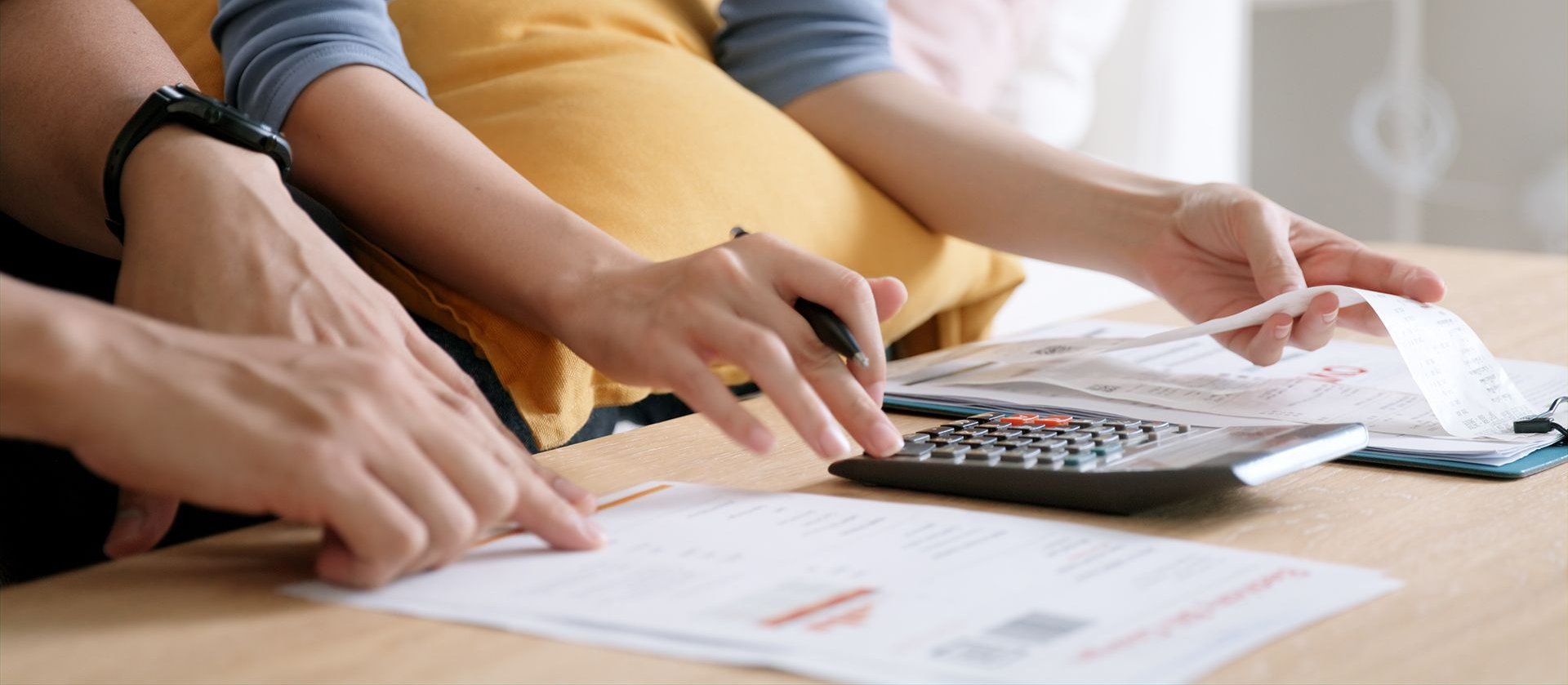 Hands working on financial documents with a calculator.