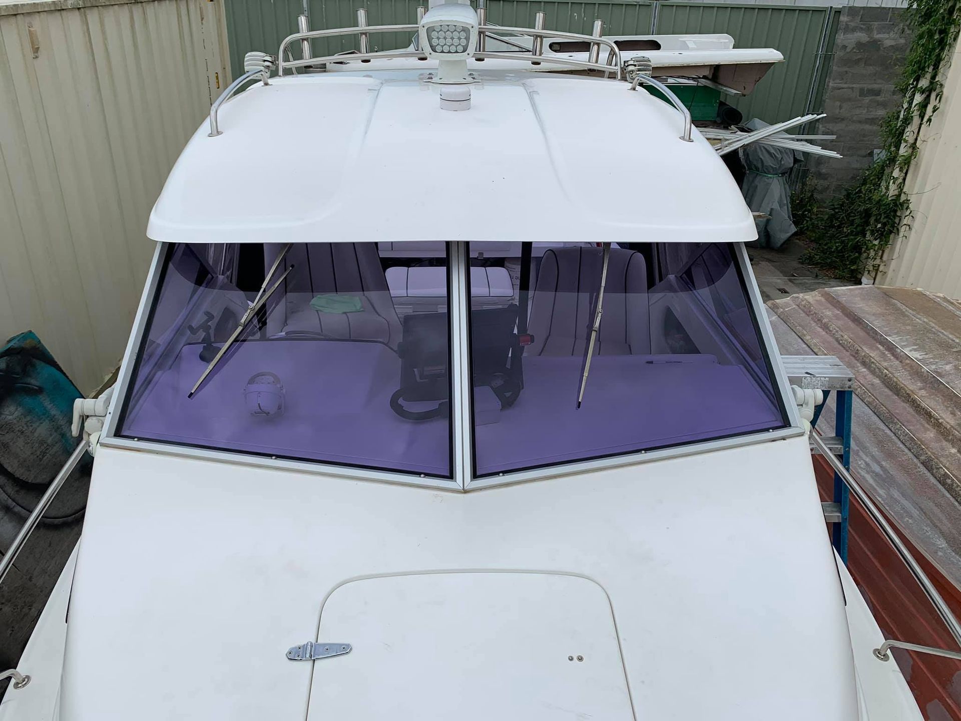 A white boat with a purple windshield is parked in a yard - Plastiglass Mid North Coast, NSW