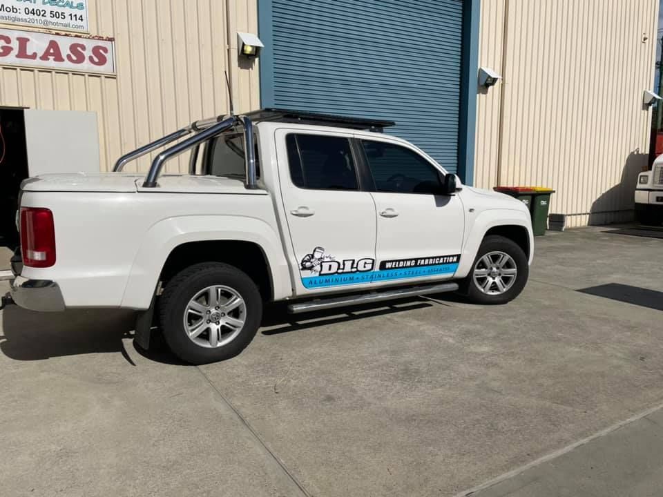 A white truck is parked in front of a building that says glass